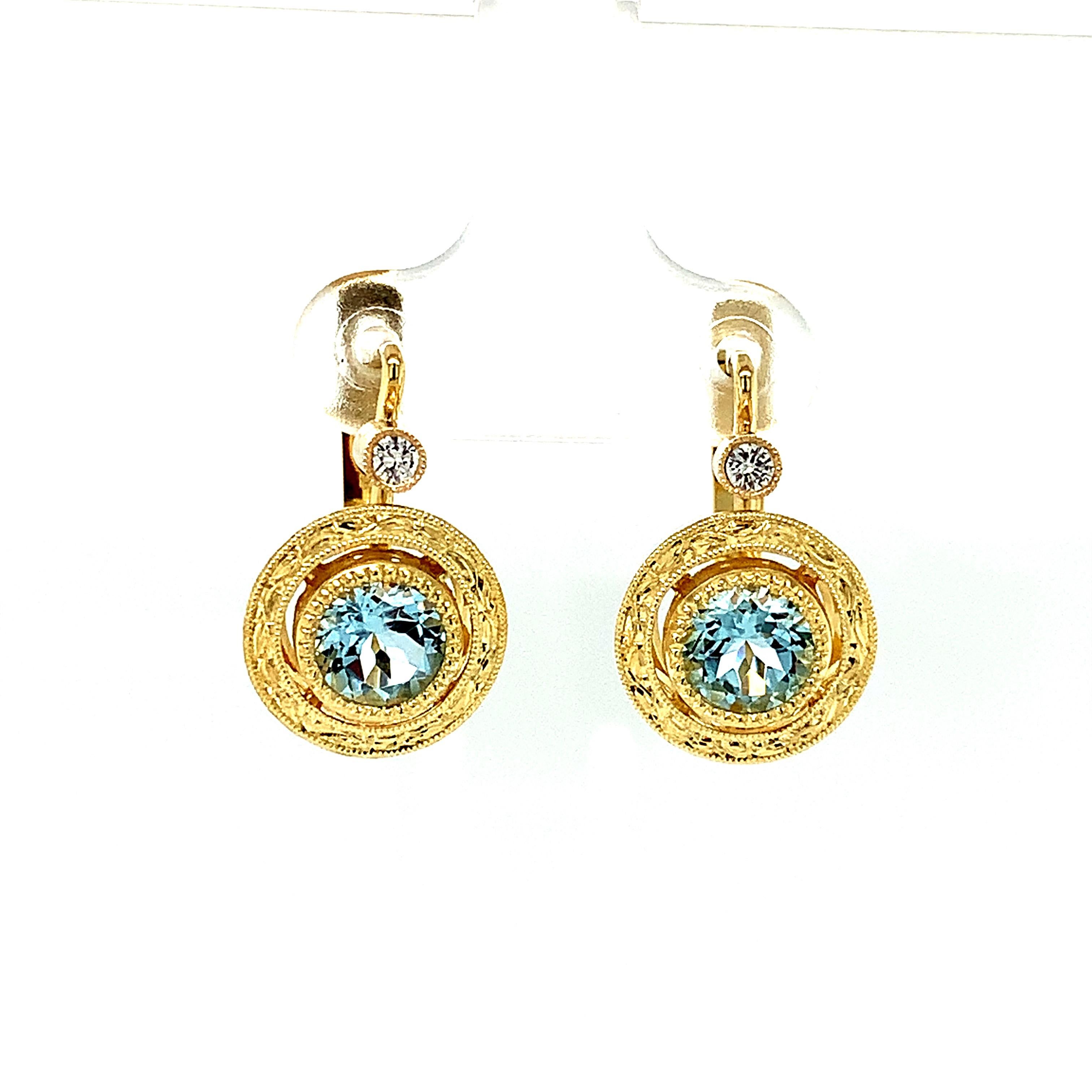 These intricately handmade drop earrings feature sparkling round aquamarines set in 18k yellow gold! The sky blue crystalline gems would light up anyone's day, especially if you are an Aquarian born in March! Beautifully set in finely engraved 18k