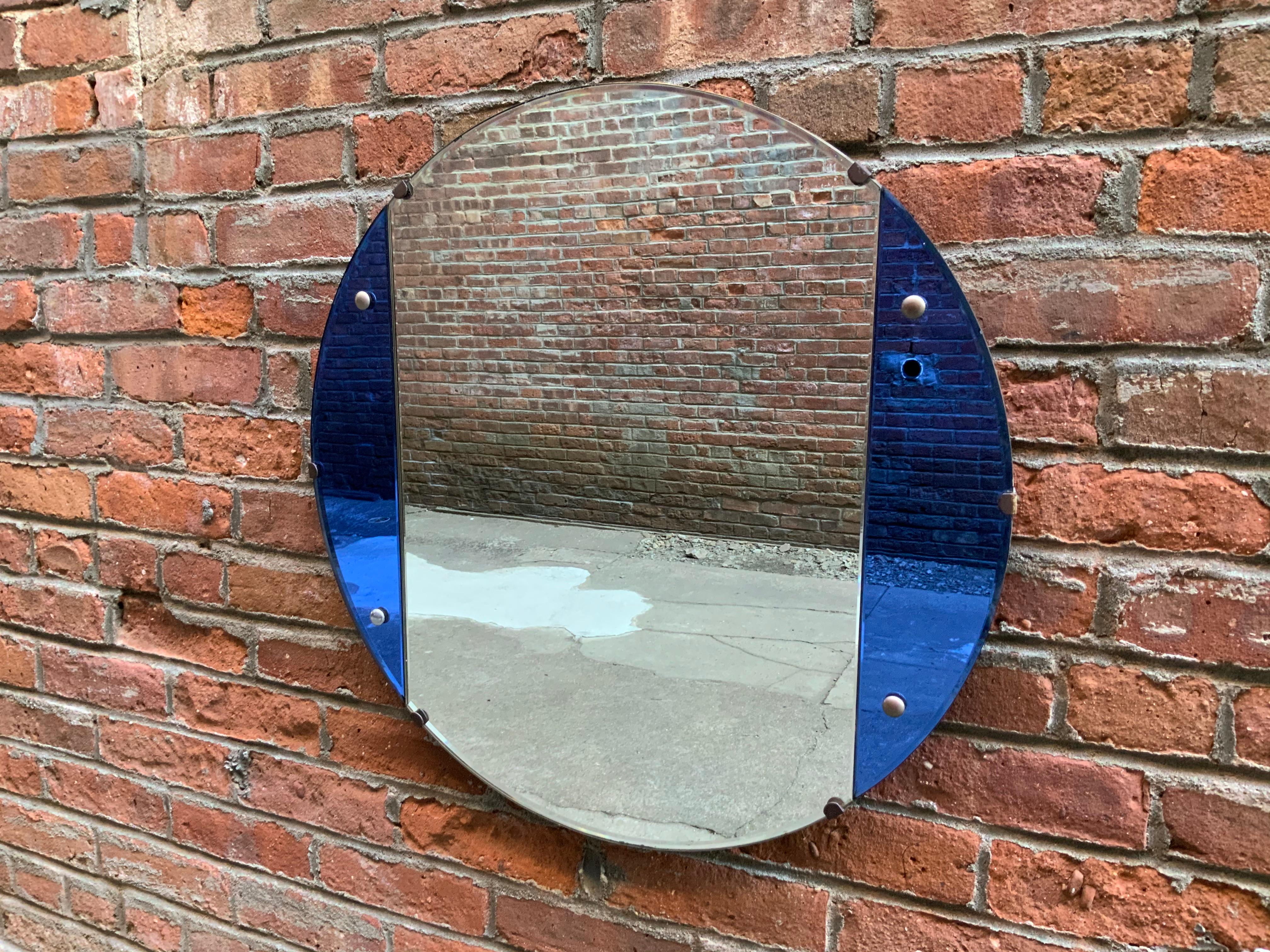 Round Art Deco blue mirrored glass mirror, circa 1930. Clear mirrored glass panel flanked by two demilune blue mirrored glass panels. Very good condition with minor silver losses and wear to the edge. Polished and bevel edge.

Measures: 23.5