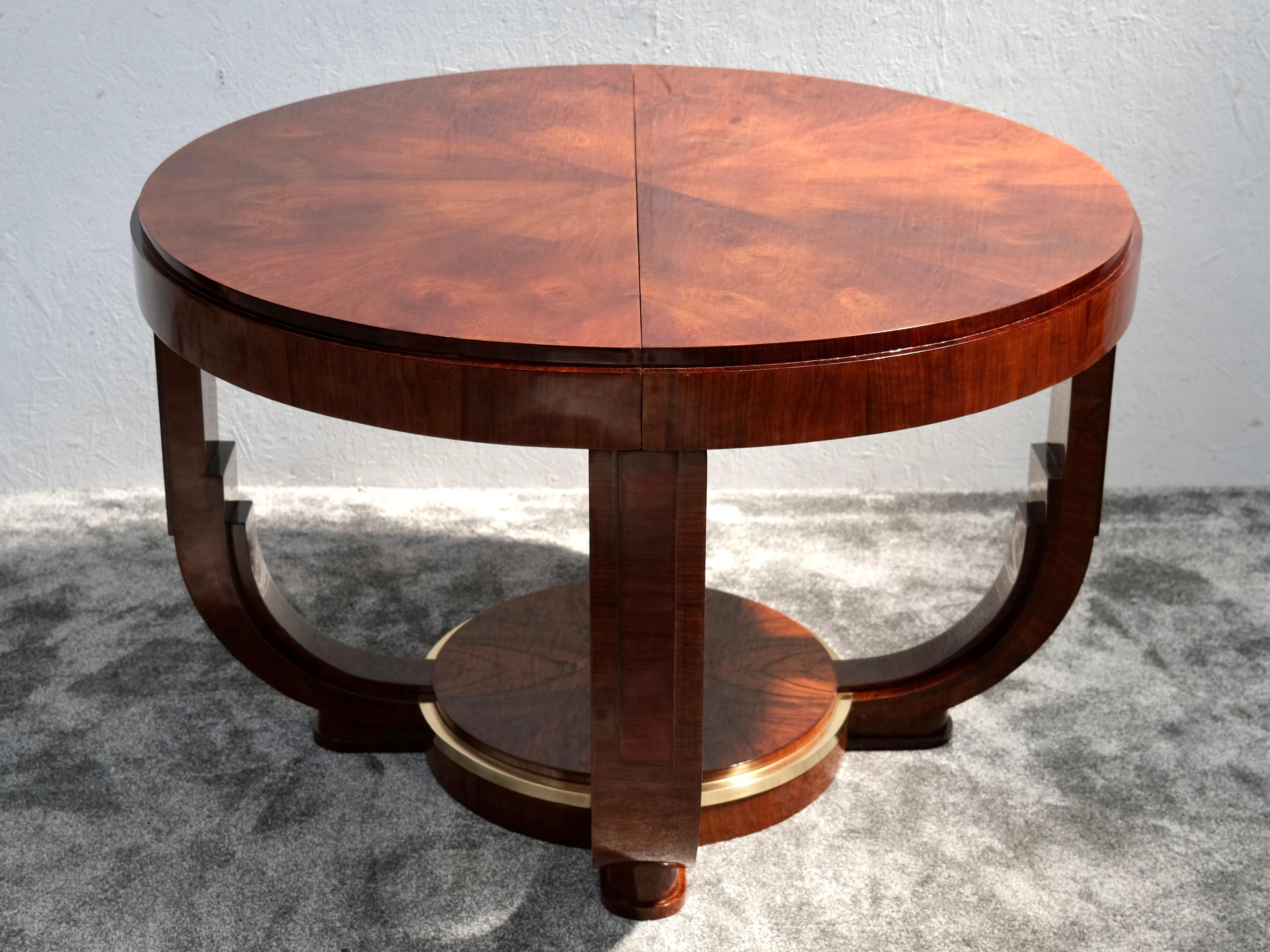 This exquisite round Art Deco dining table embodies the elegance of 1930s design while offering smart versatility. Crafted from French walnut, its perfectly balanced silhouette rests on sculptural, stepped legs that merge into a central circular