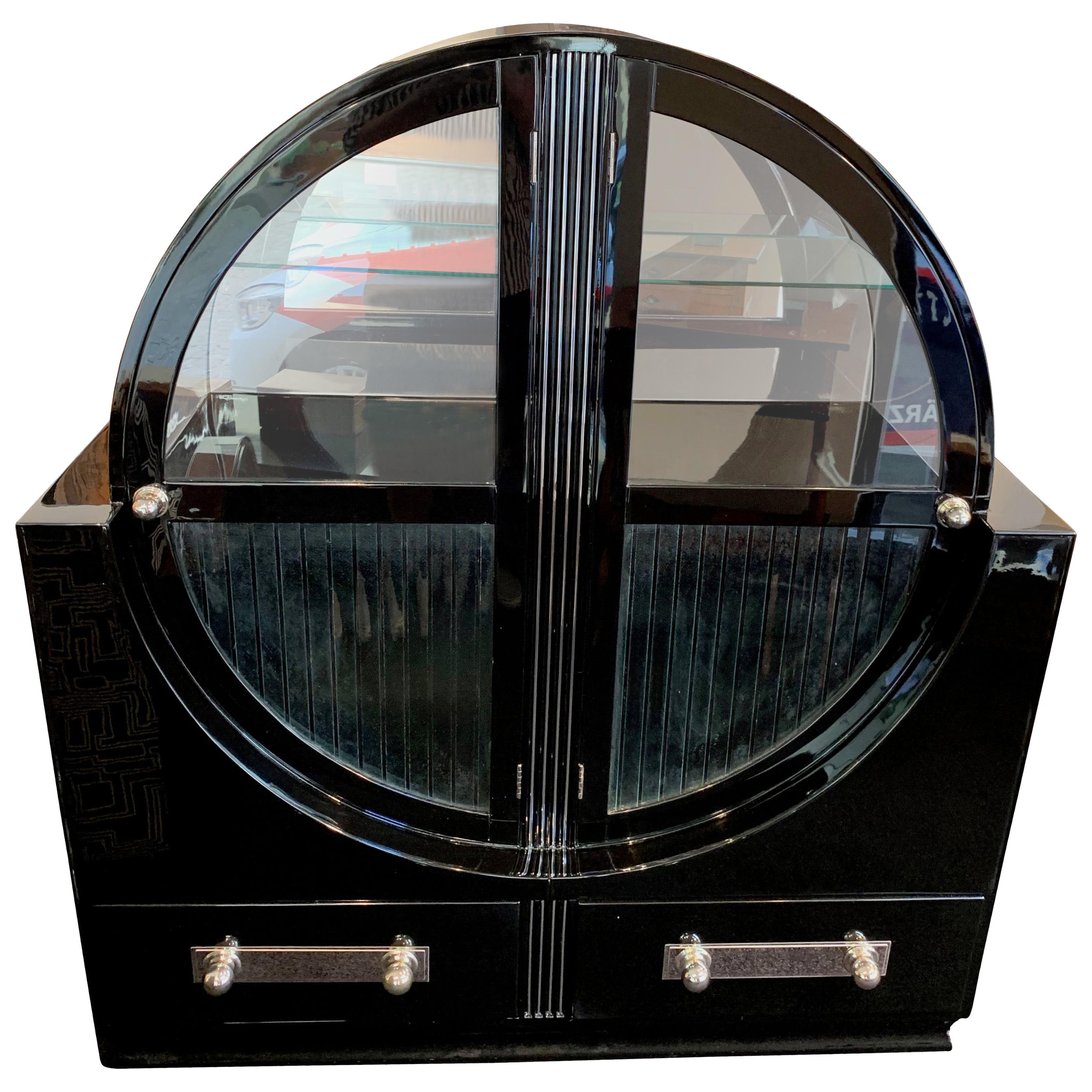 Extraordinary round Art Deco showcase vitrine

Black piano lacquer, high-gloss polished. Original glass windows.

Inside with 2 black wood plates and 1 glass plate. Upper half inside with mirror glass in the back
Cannelured front with chrome