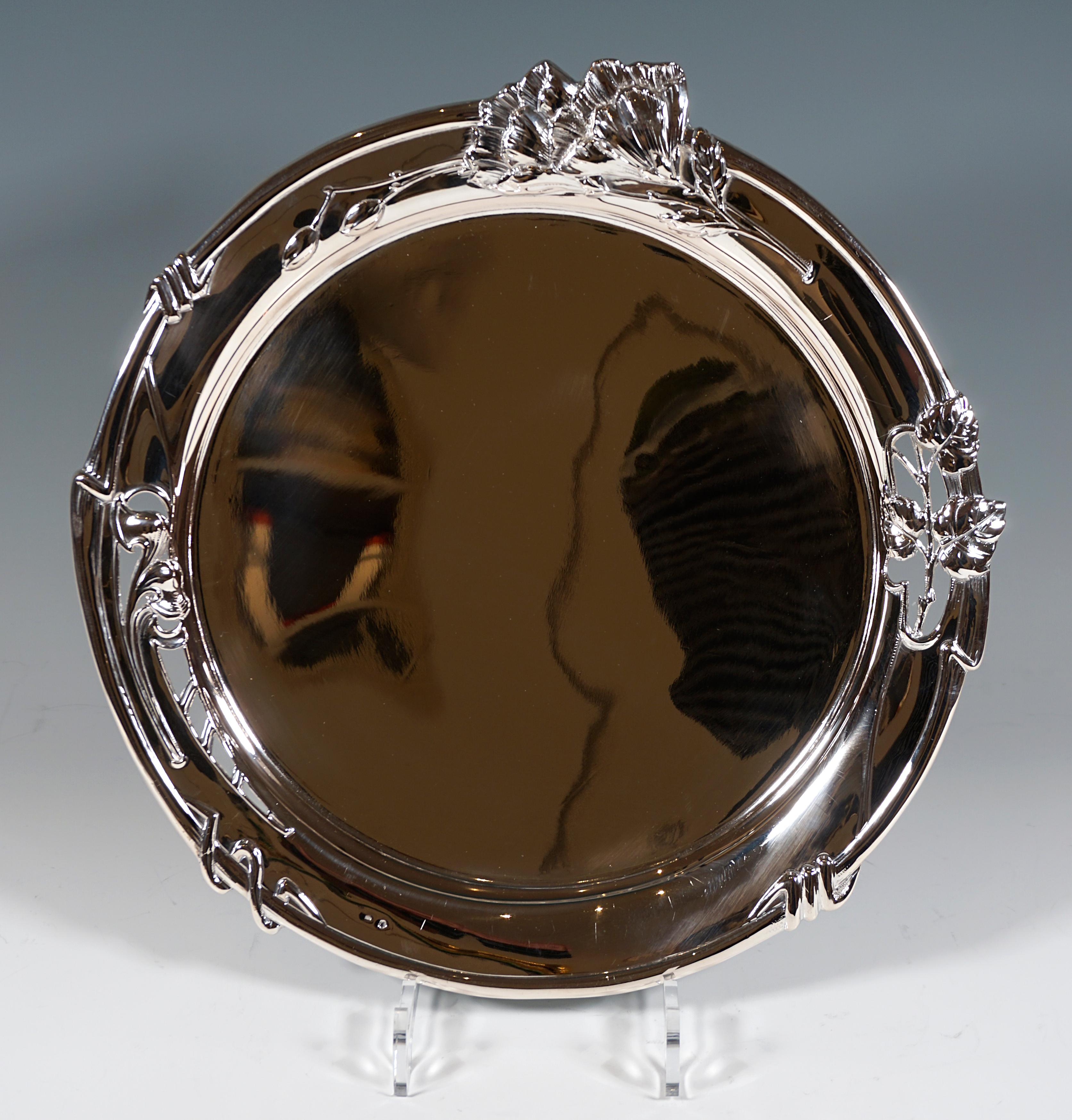 Decorative round silver tray with smooth mirror, rim decorated by floral relief and openings.

Hallmarks:
Diana's head + 'C' - Austria-Hungarian official hallmark 1872-1922 for 800 Silver, Prague
Manufactory brand 'J.M' polygon framed

Total