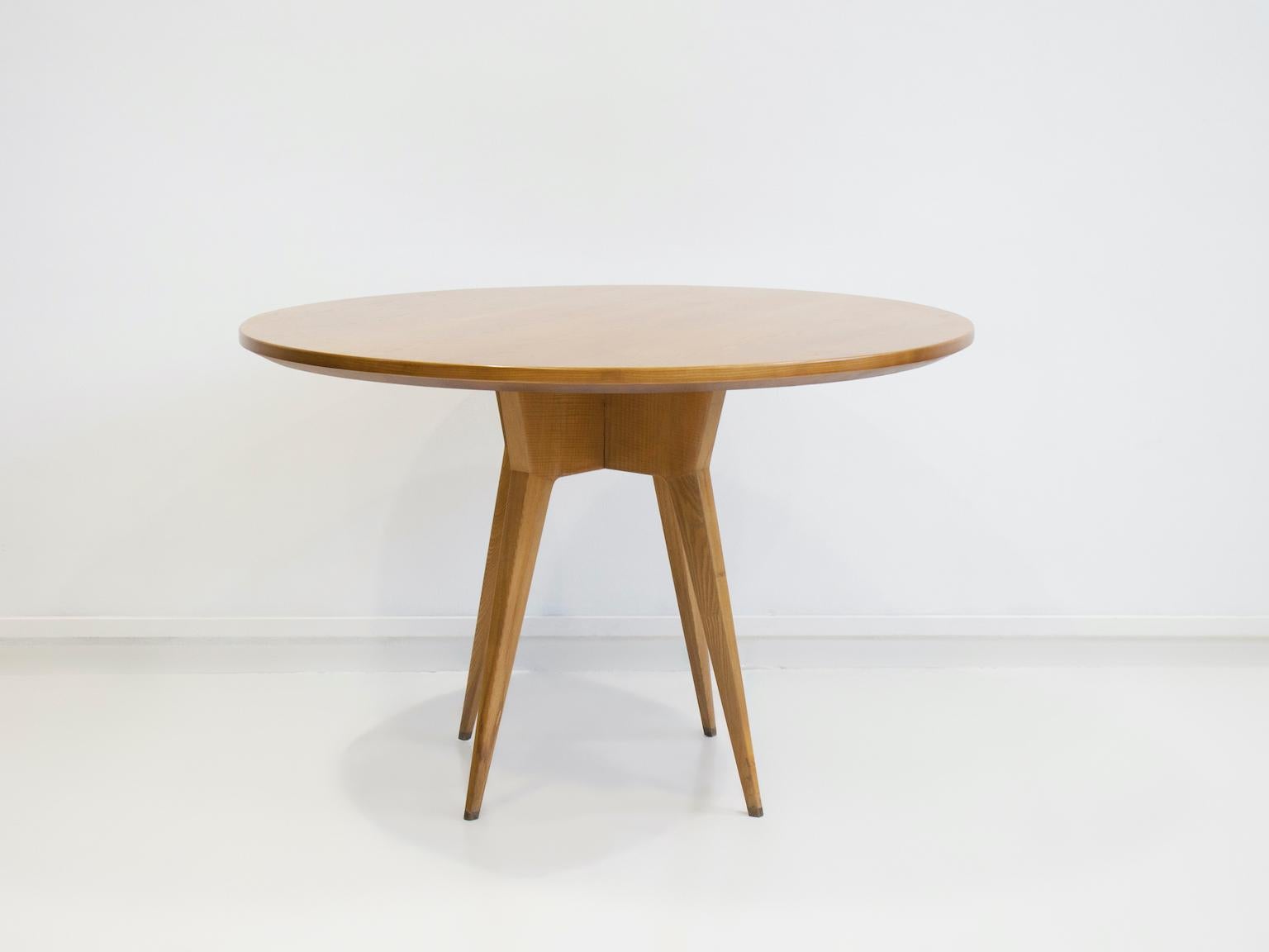 Elégante table de salle à manger ronde du milieu du siècle en bois de frêne, vers les années 1950, Italie. Dotée d'une base magnifiquement sculptée avec des pieds effilés et une finition chaude et naturelle, cette pièce incarne un design moderniste