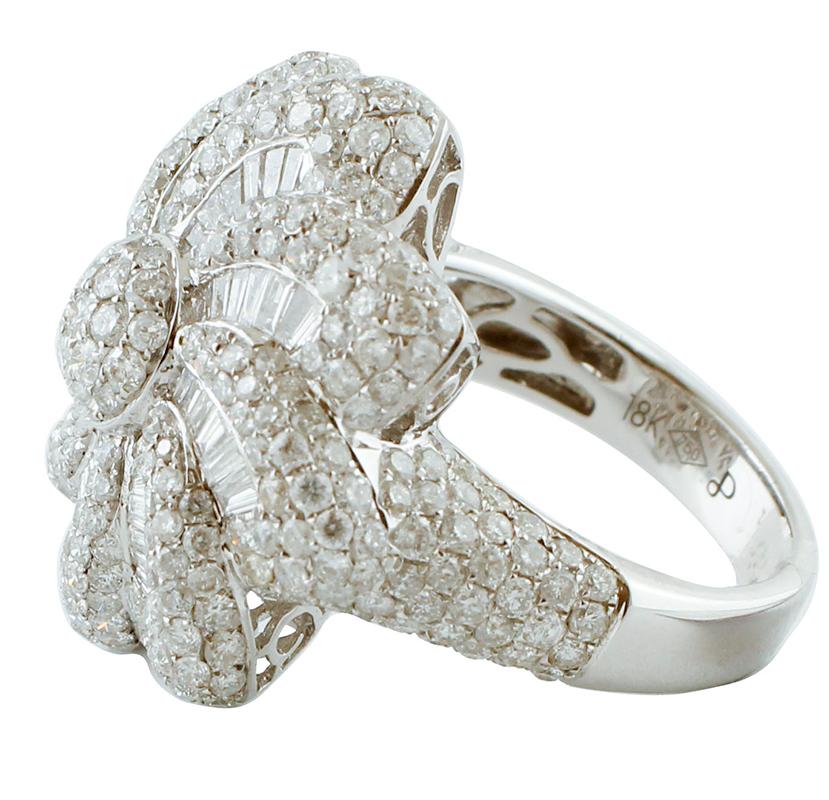 Marvelous ring in 18k white gold structure with flower design, set with 3.51ct of beautiful white round diamonds and 0.64ct of baguette diamonds.
The origin of this ring goes back to the 1980s, it was totally handmade by Italian master goldsmiths