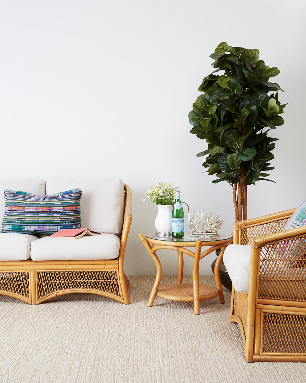 Mid-Century Modern bamboo and rattan two-tier drink table having a round glass pane top. Constructed from steam bent rattan to form a round base with a lower shelf covered with cane. Interesting profile with bent legs and arched stretchers.