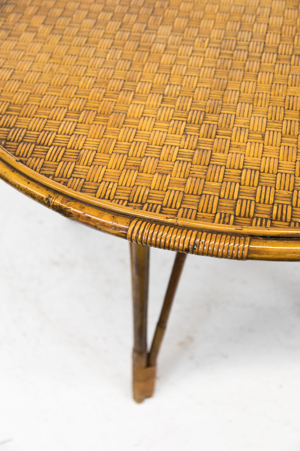 Round bamboo table has four triple bamboo legs bound at the bottom with rattan strapping. The top is made with interlaced split rattan and framed with a 1/8” and a 3/8” band.
 