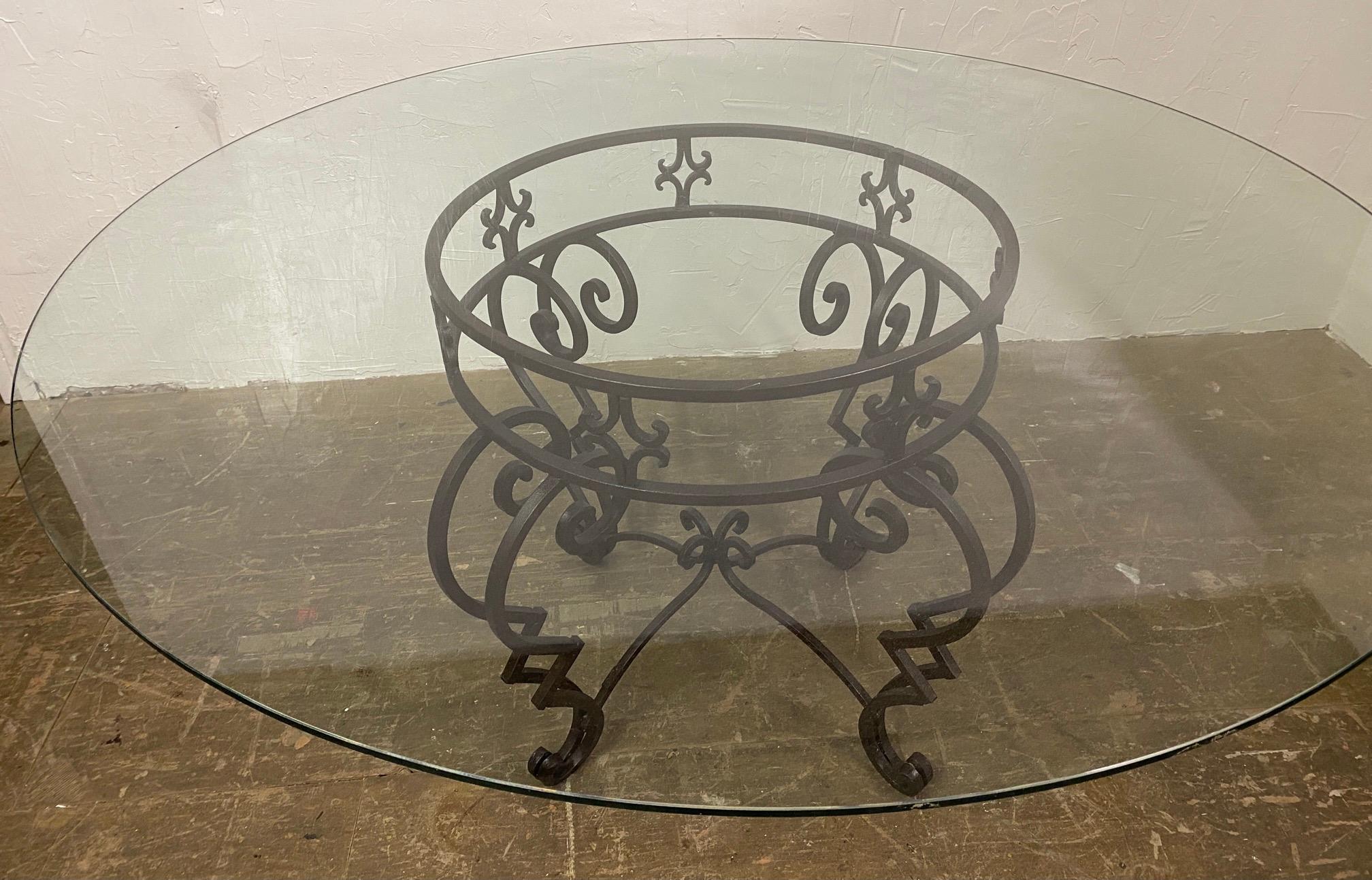 Crafted in the USA, the elegant wrought iron circular base features a circular top supported by 4 cabriole legs tied together with stretchers coming together in the center. Table base is in excellent condition. The glass top shows much wear and is