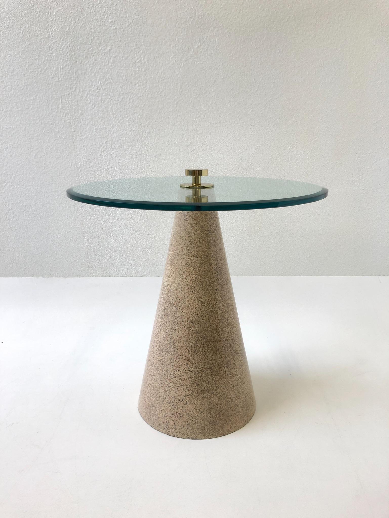 1980s Postmodern cone shape side table. The base is constructed of wood with a lite blush faux granite lacquered finish, the beveled glass top is joined to the base by polish brass hardware. The table is in original condition, so it shows minor wear