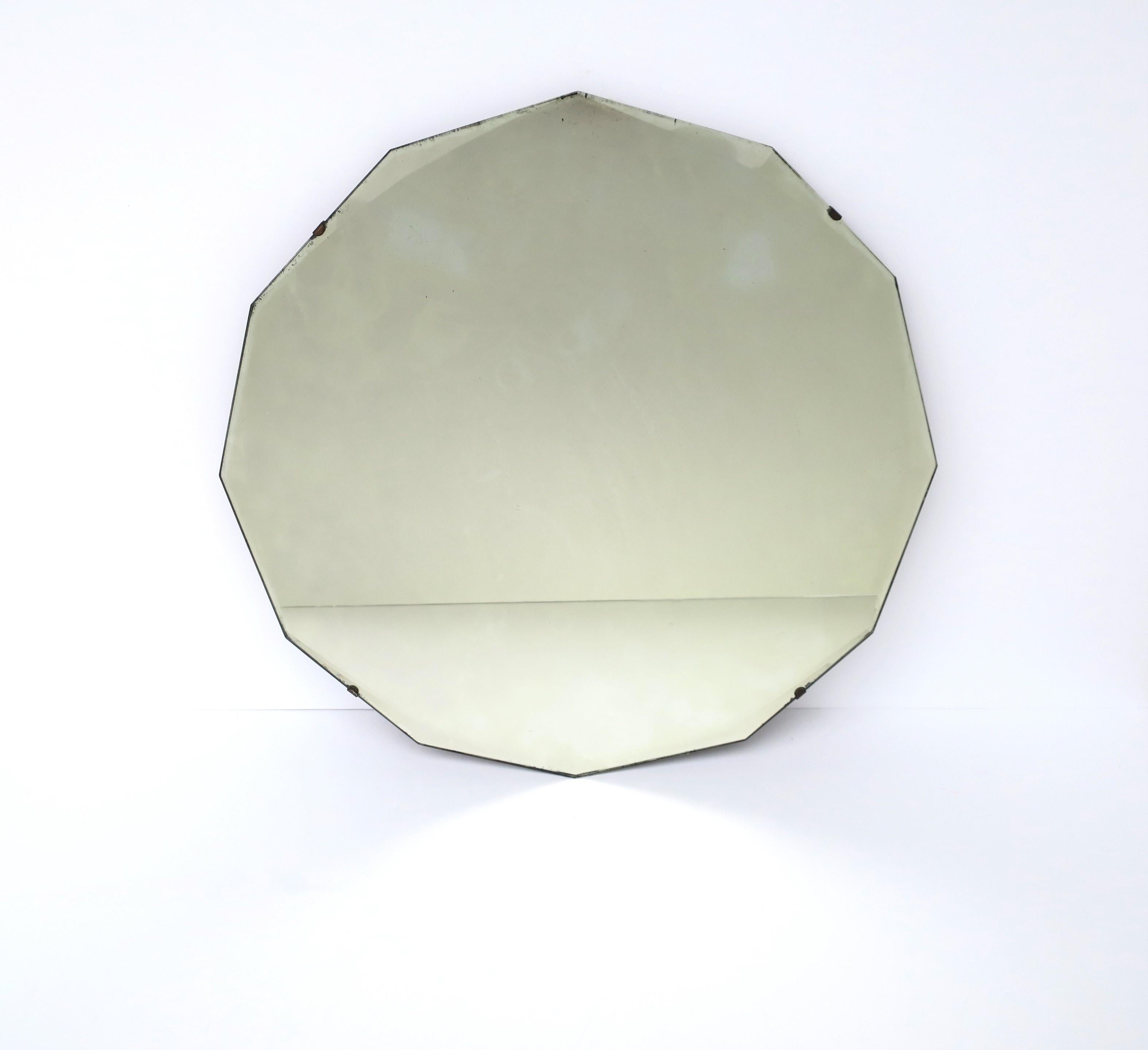 A round 12 sided (dodecagon) beveled edge wall glass mirror, in the Hollywood Regency style, circa early-20th century, 1940s. Beautiful intersecting bevel at each point (12) around mirror's edge. Piece may work well for a foyer, vanity, dressing