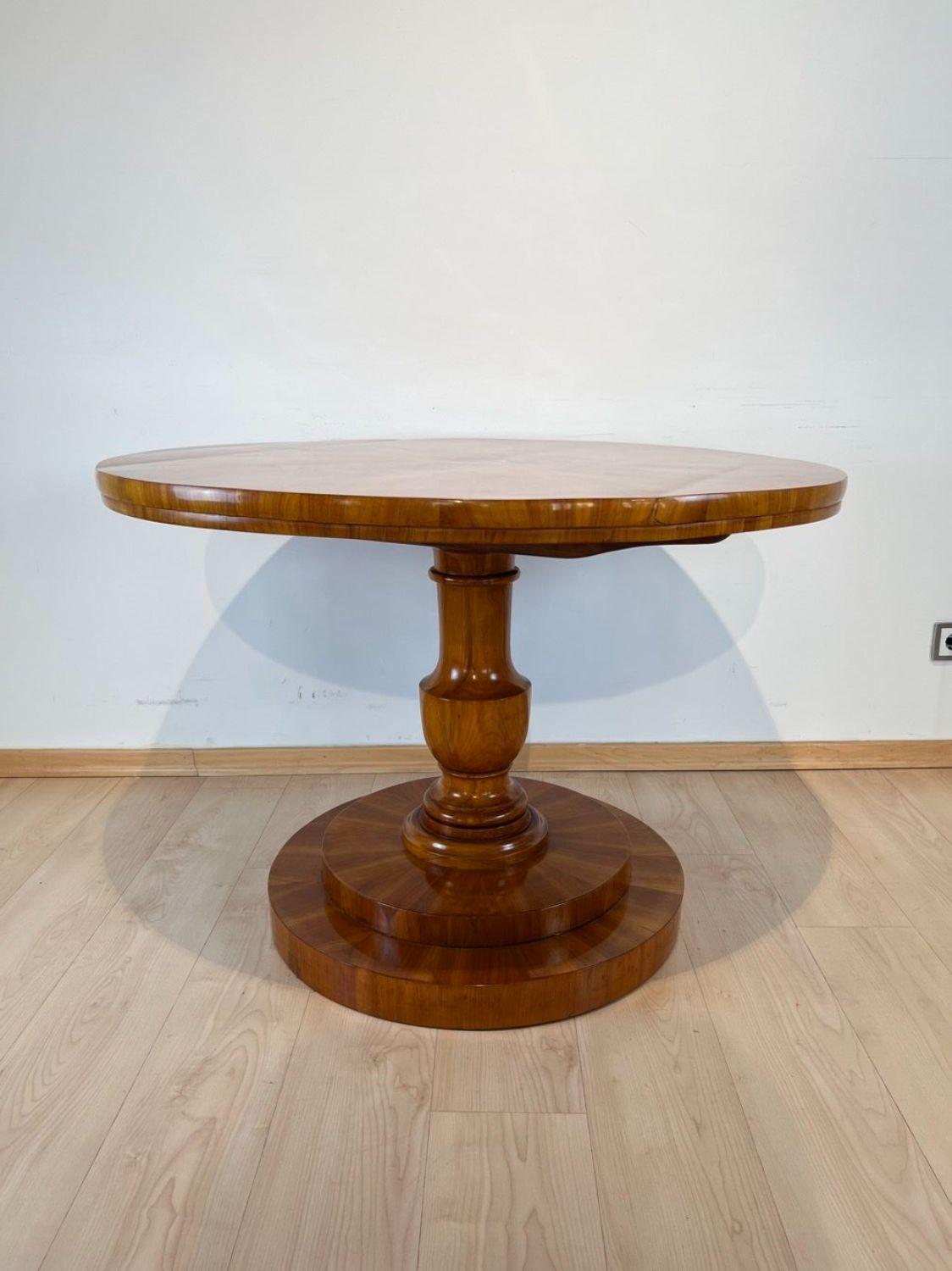 Elegant round Biedermeier Center Table from Austria, Vienna around 1830.

Star-shaped cherry veneer on softwood top with round ebony inlaid in the center. Pedestal carved from solid cherry wood.
Beautiful cherry veneer ion the tiered base.

Plate