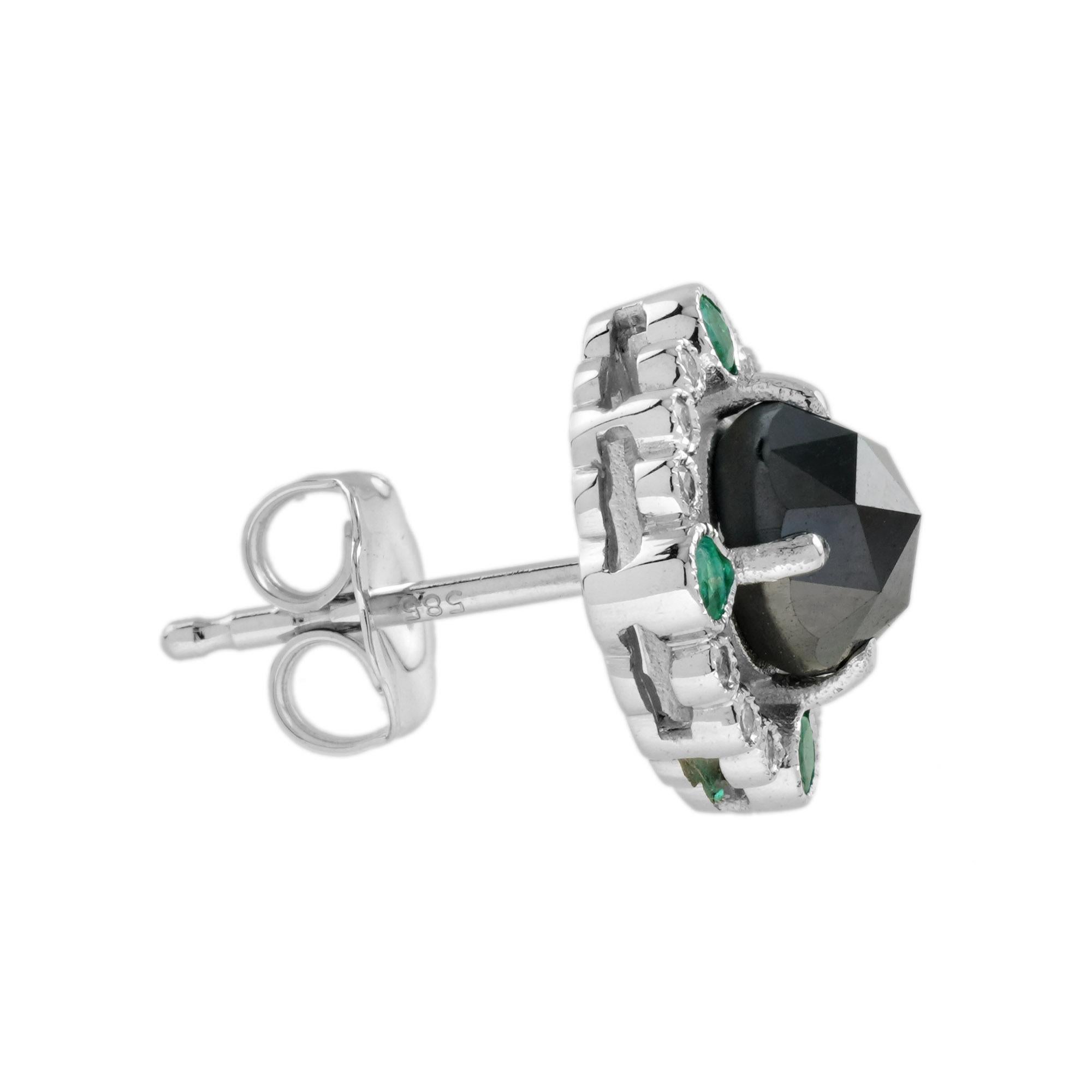 Black diamonds are surrounded by glittering halos of eight white diamonds and four emeralds on each piece. Glamorous and elegant, these stud are perfect to wear day and night. 
Earrings Information
Style: Art Deco
Metal: 14K White Gold
Width: 12