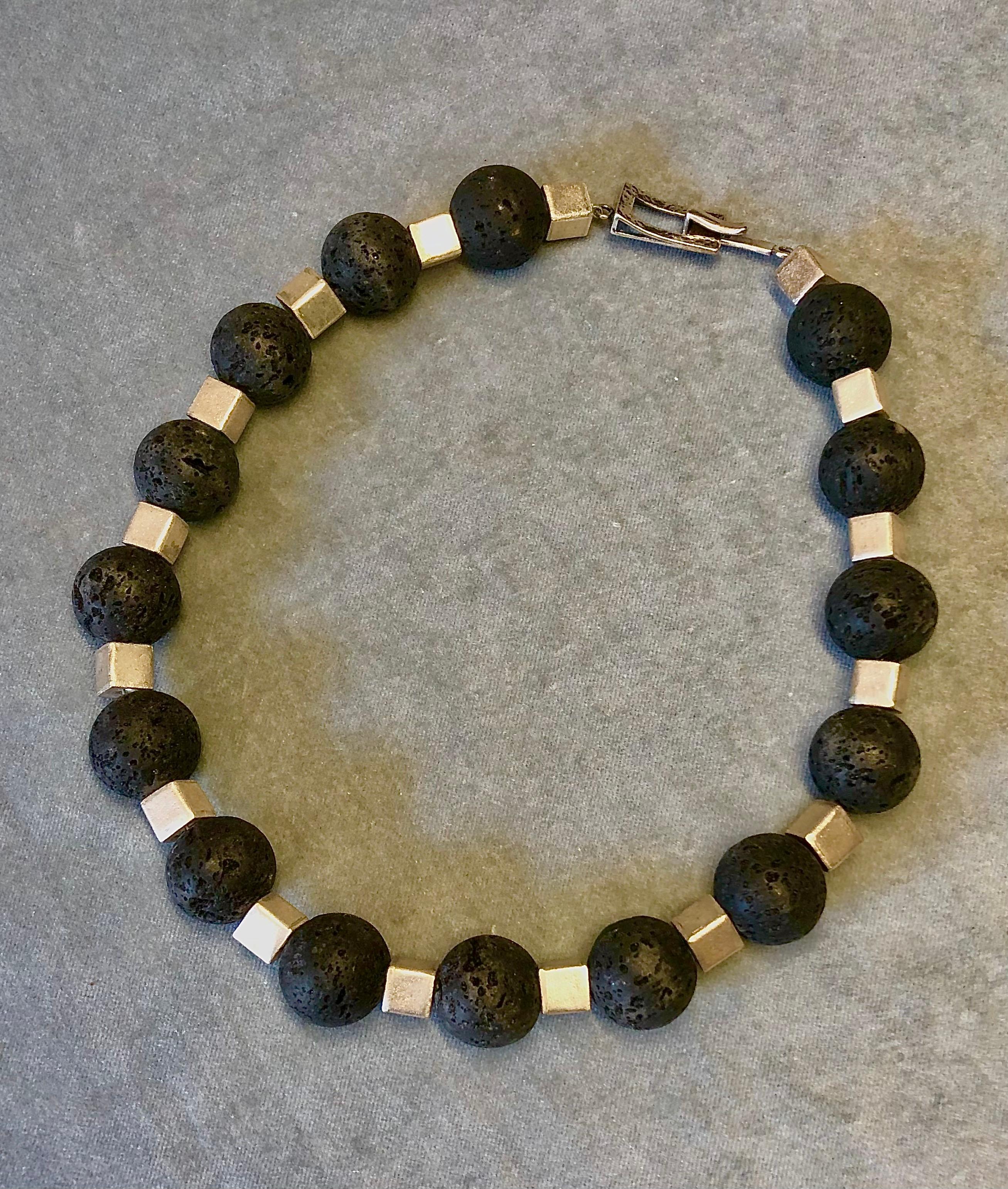 Single strand necklace. Round black lava beads, square white metal spacers and sterling silver toggle clasp. 