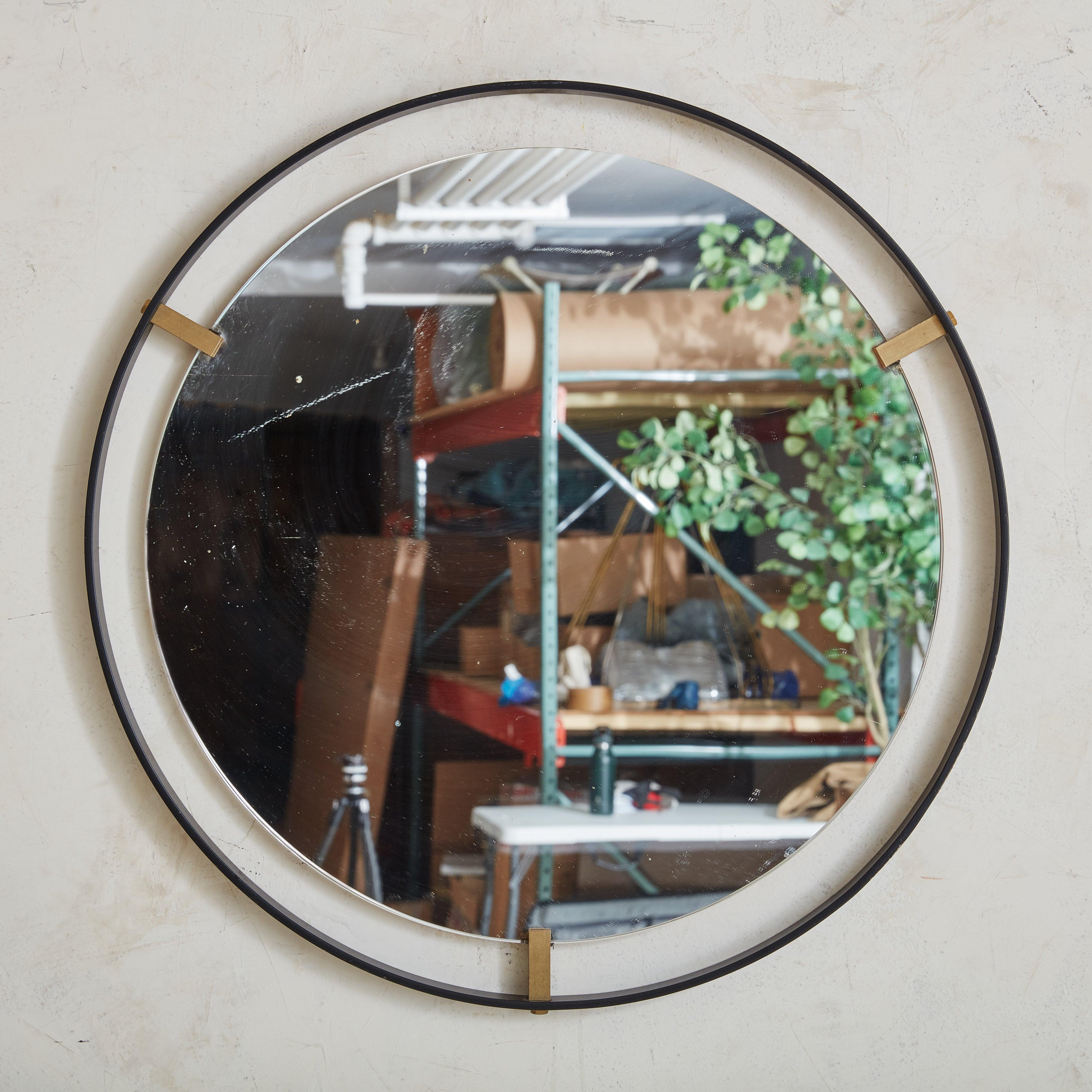 A vintage round wall mirror featuring a minimalistic black metal frame. Patinated brass notches secure the frame to the glass, giving this piece an elegant floating effect. 1980s.

Condition: Great vintage condition. Minor marks along the edges of