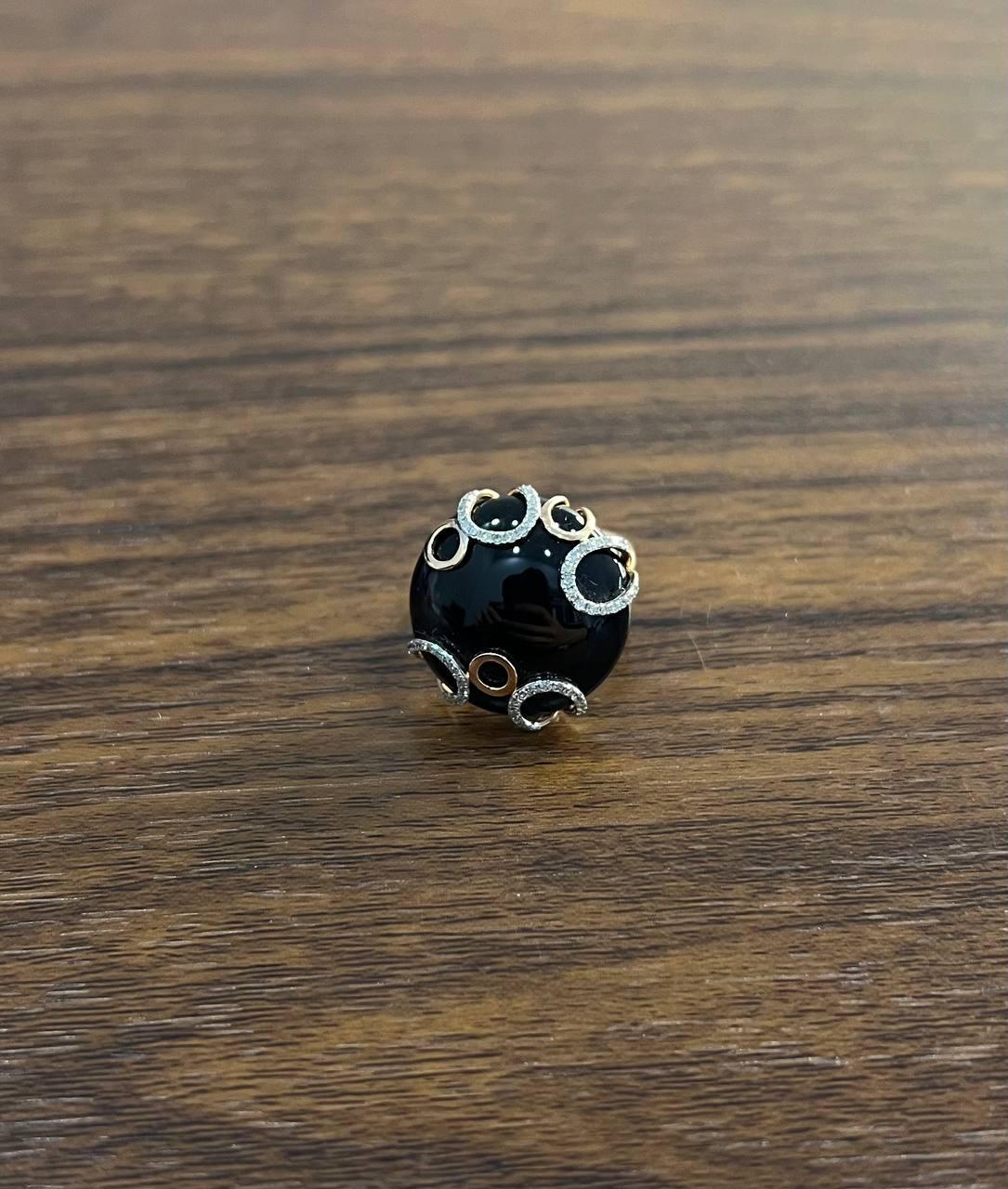 A striking and unique ring. This piece features a bold black onyx set in a 14k rose gold band. The stone is adorned with intricate circular accent diamonds (0.30ctw), adding a touch of elegance and complexity. A captivating accessory that makes a