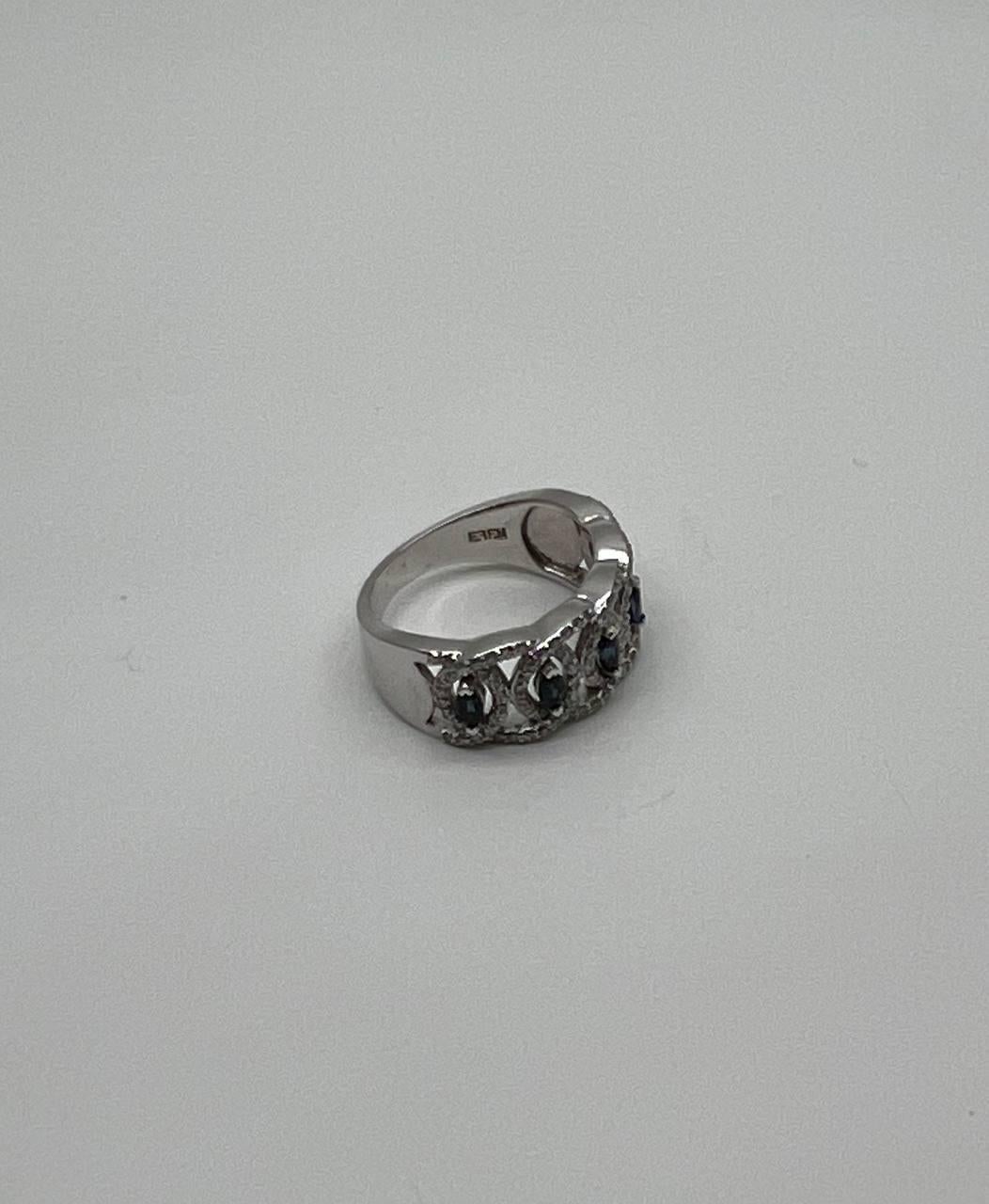 A study in elegance, depth, and shimmer. This striking ring features a series of deep blue sapphires, each encased in a delicate, intricate setting. The stones are beautifully aligned, creating a continuous band of color and sparkle. The band is