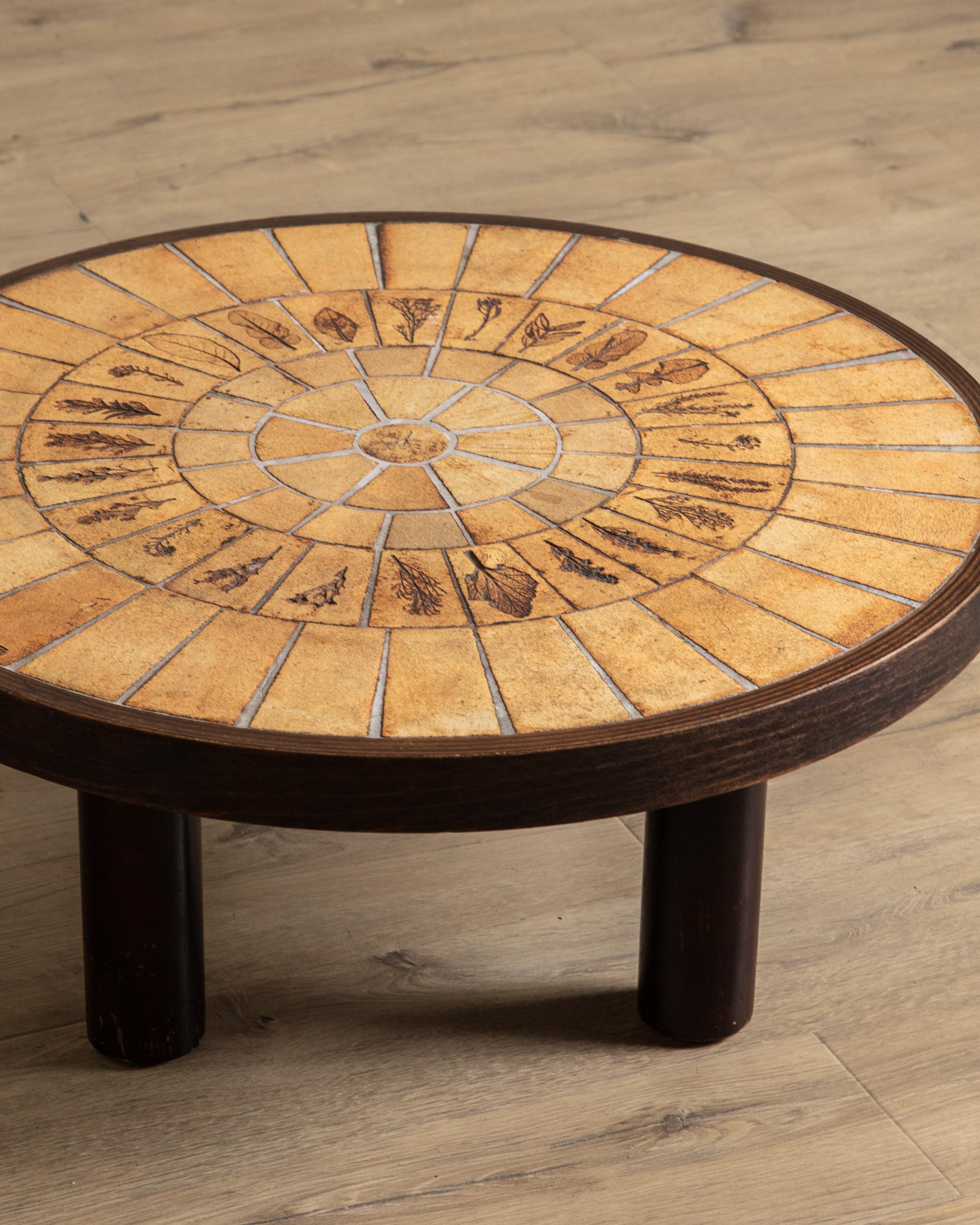 Dieser runde französische Couchtisch, der von Roger Capron gestempelt und auf ca. 1965 datiert ist, zeigt die für den Künstler charakteristischen botanischen Motive im Stil der Sonnenstrahlen in einer wunderschön komponierten Kachelplatte. Die
