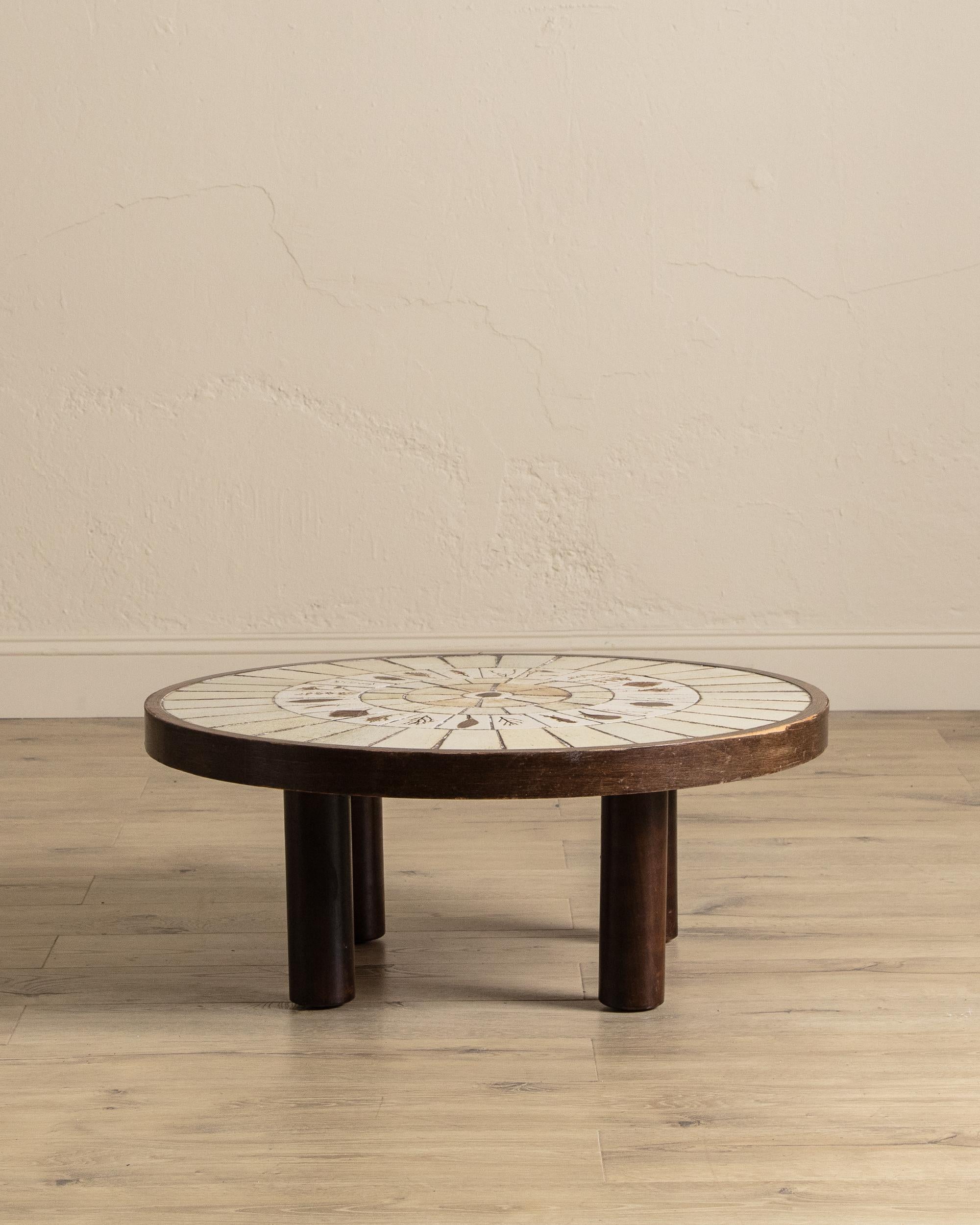 Dieser runde französische Couchtisch, gestempelt Capron und datiert ca. 1965, unterstreicht die Kunstfertigkeit von Roger Caprons berühmten Keramikarbeiten aus der Mitte des Jahrhunderts. Die wunderschön komponierte Kachelplatte zeigt eine Anordnung