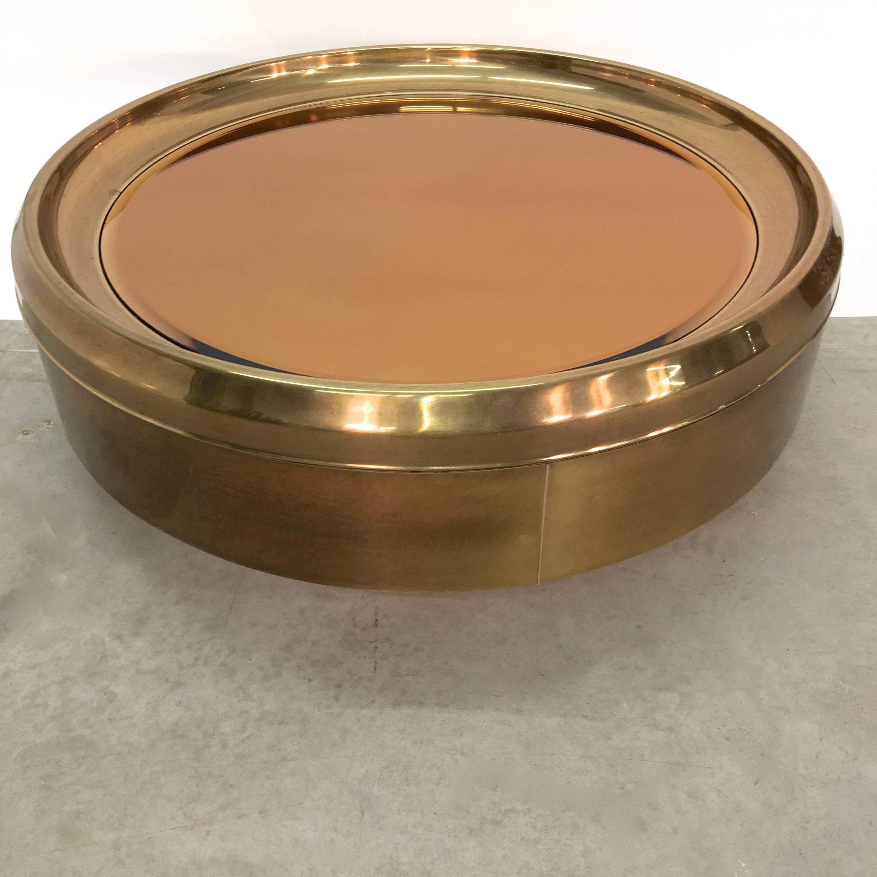 1970s Mastercraft large-scale circular brass porthole form coffee table with beveled bronze mirror top on brass clad drum and recessed platform base.

Measures: 43.5 inches diameter. 15.5 inches high.

 