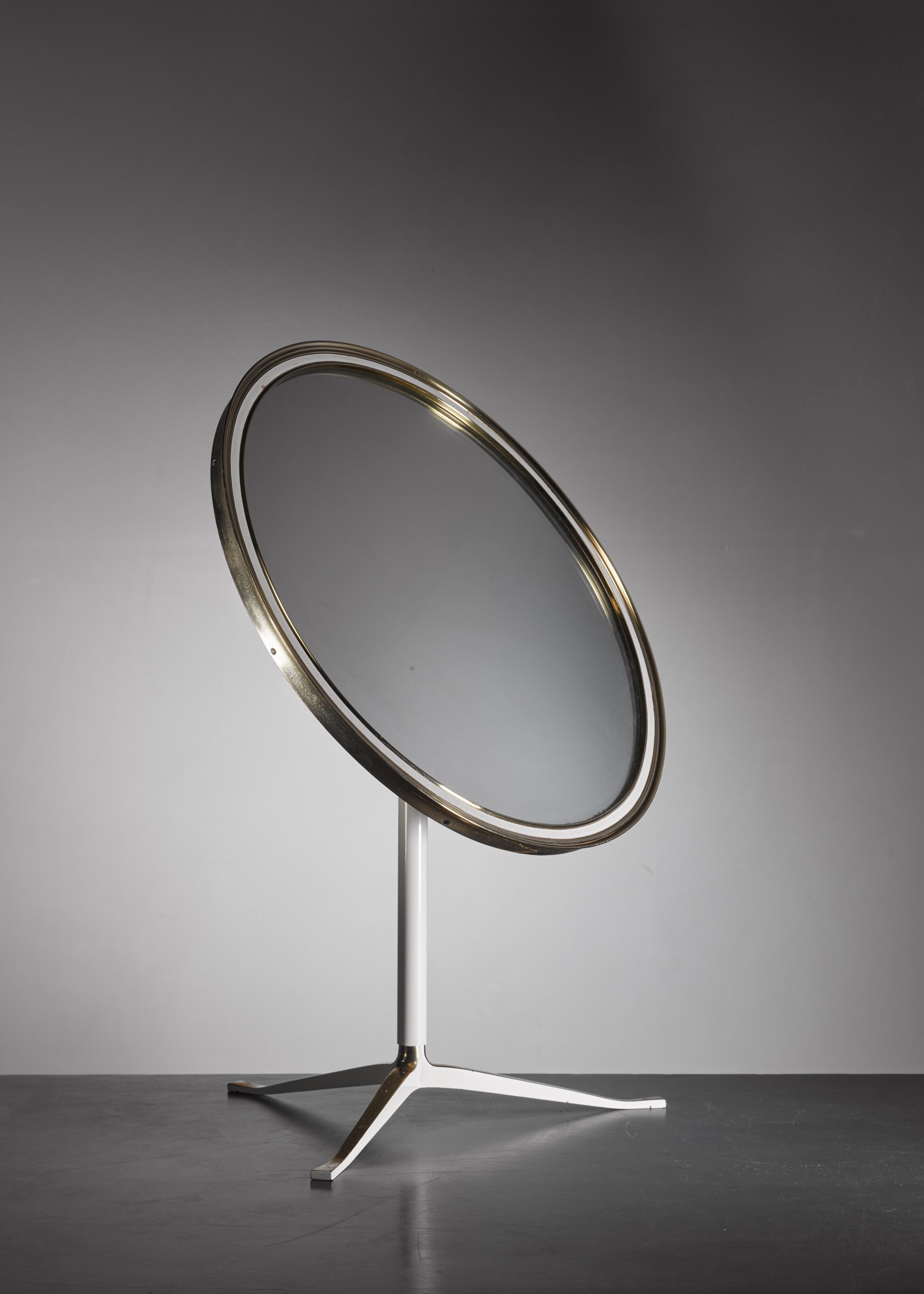 An elegant 1950s brass table mirror on a tripod foot. The stem and parts of the foot are lacquered white and the frame has a white strip inside. The back of the mirror has the original fabric cover. In a great vintage condition.