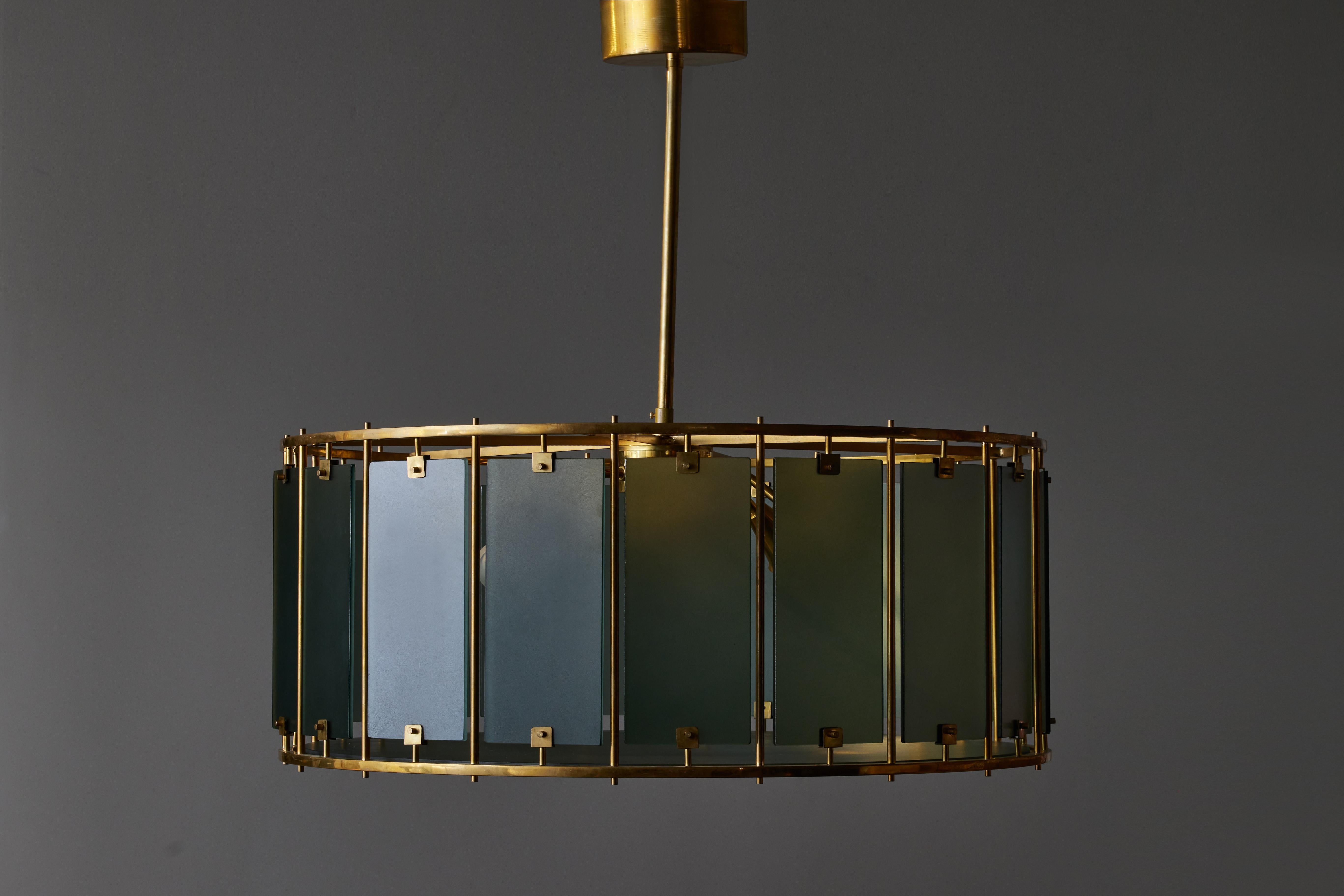 Round chandelier made of a brass structure, setting frosted glass panels which act as diffusers for the six sources of light inside the chandelier.