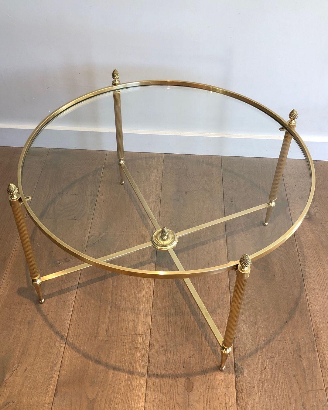 This neoclassical style round coffee table. is made of brass with a stretcher and 4 elegant brass finials. This is a French work by famous Maison Baguès. Circa 1940.
 