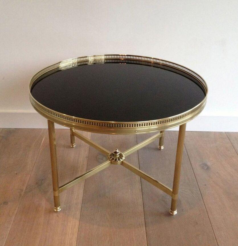 This round coffee table is made of  brass with a black lacquered glass top. This is a French work by Maison Jansen. Circa 1940
