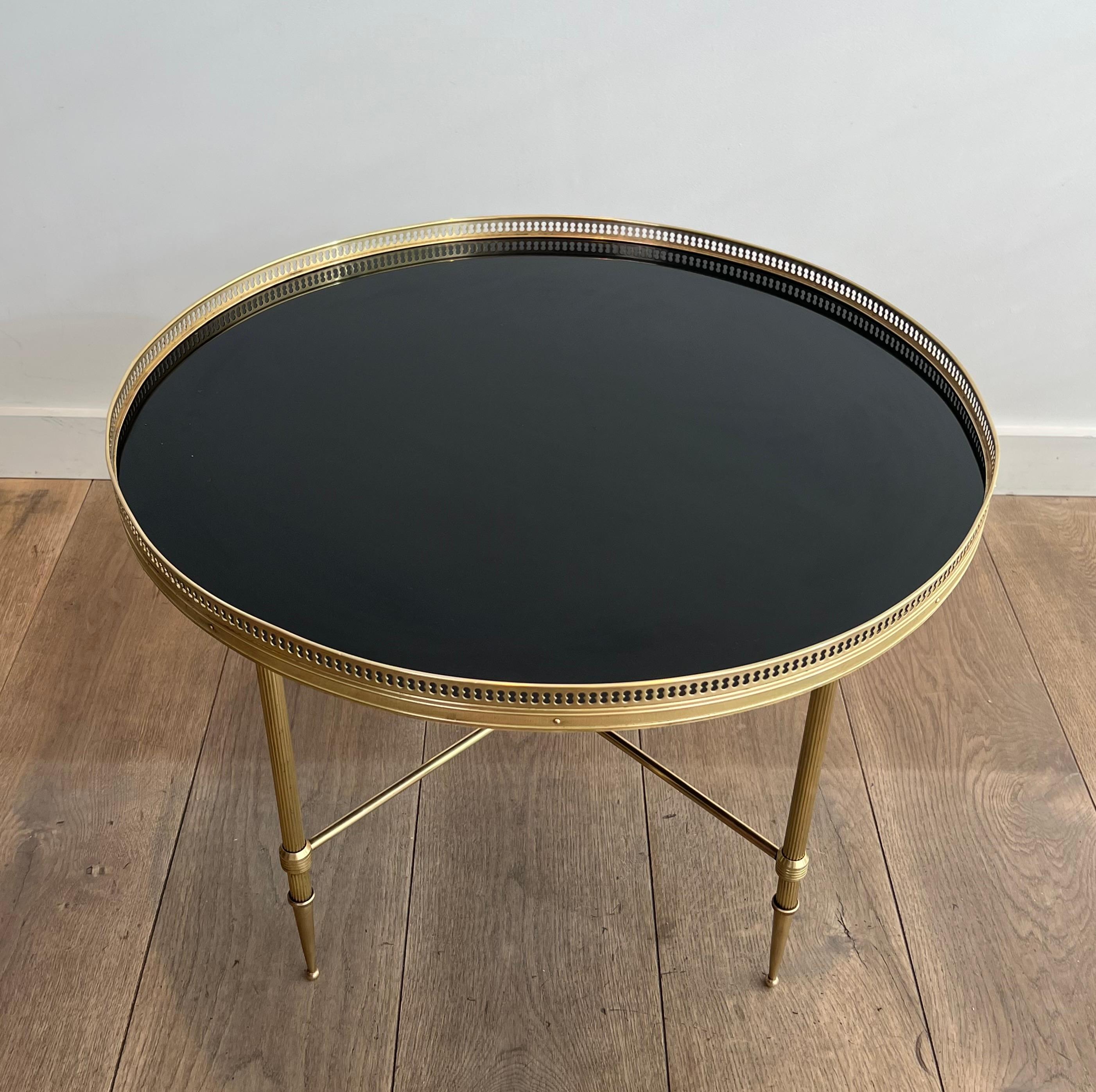 This very nice and decorative round coffee table is made of brass with a black lacquered glass top. This is a French work by Maison Jansen. Circa 1940