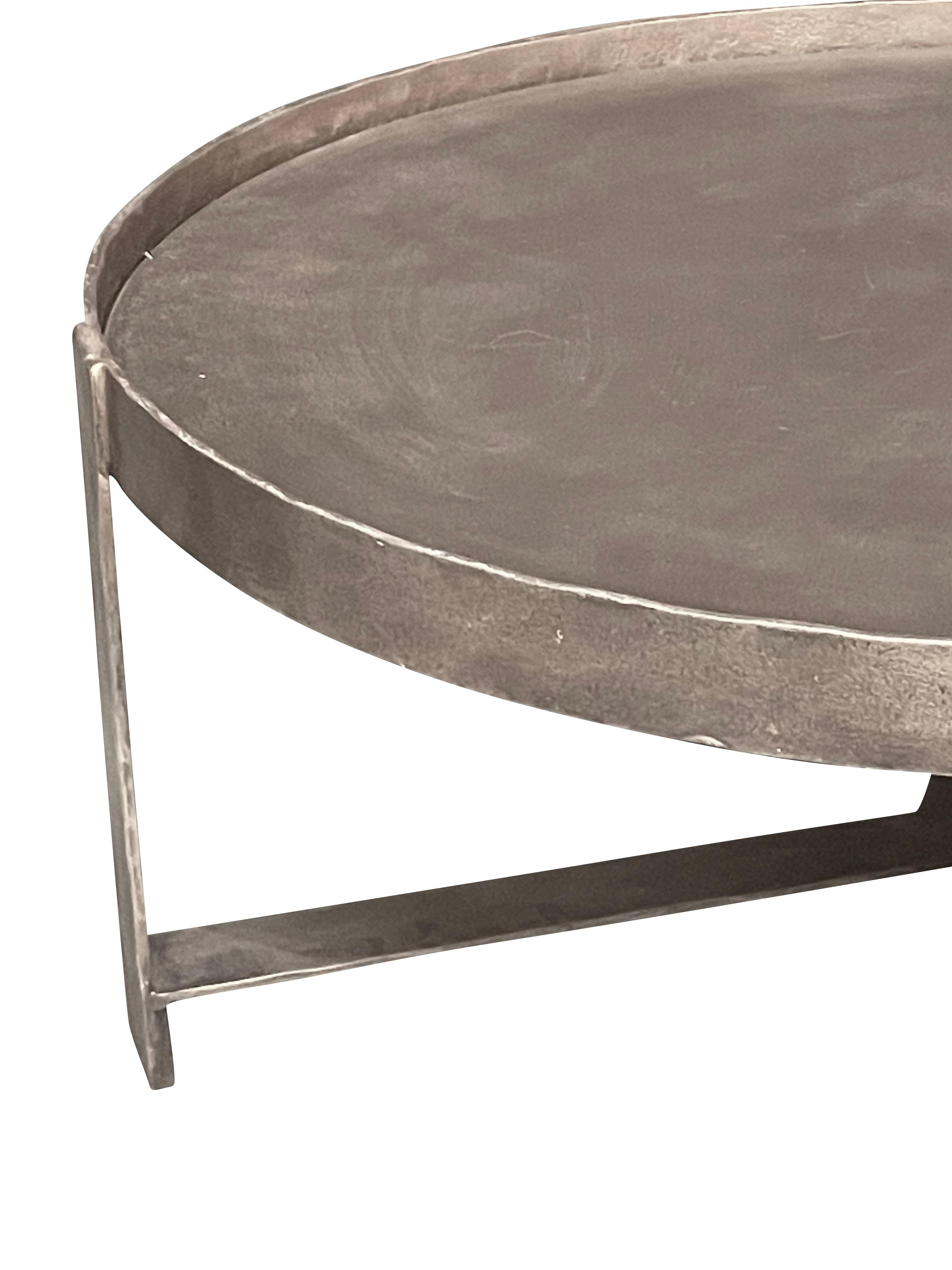 Contemporary Indian round brass coffee table with raised surrounding lip. 
Top supported by self tripod leg X stretcher base.

 
