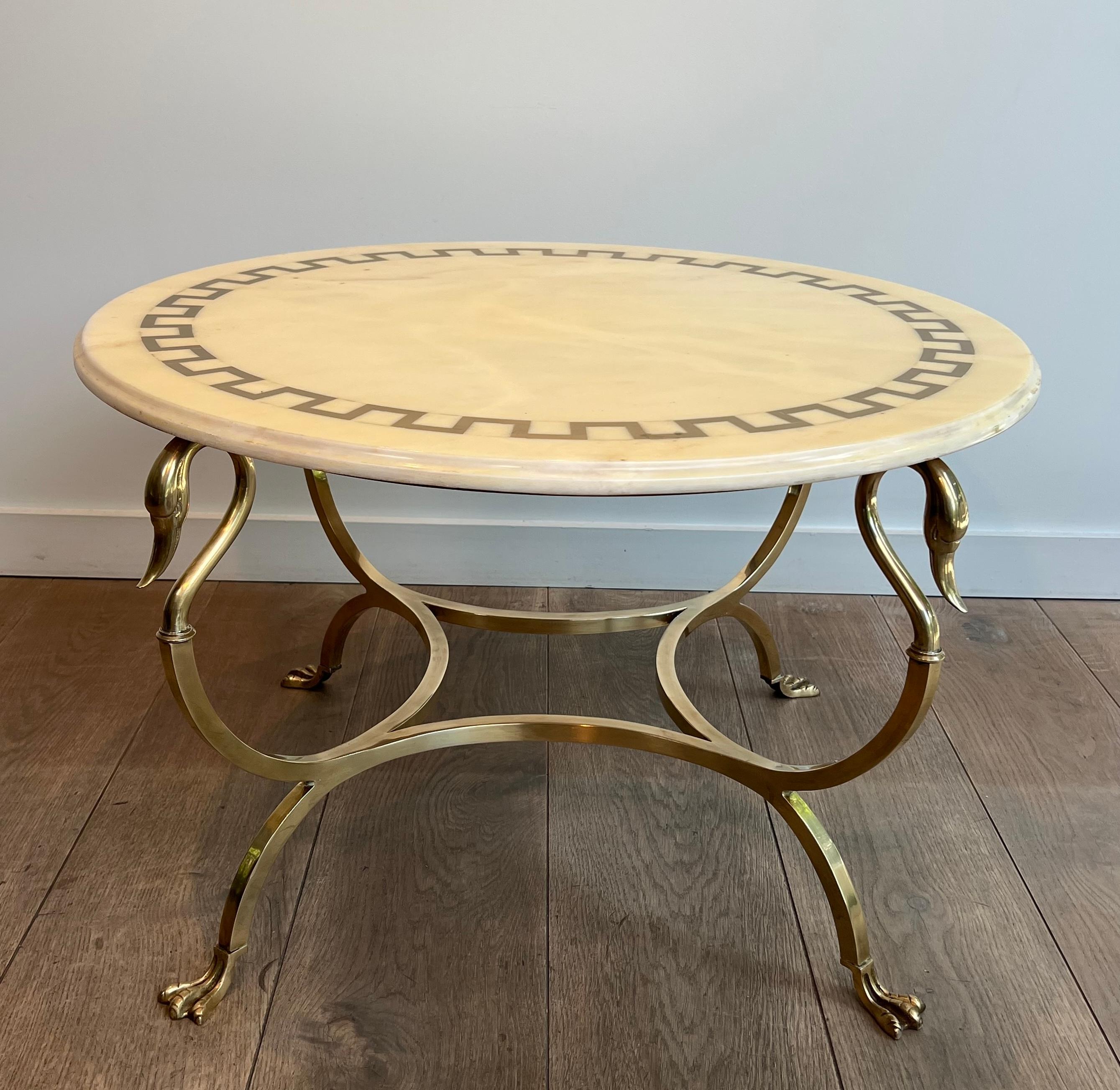 This very nice neoclassical style round coffee table is made of brass with swan heads and feet topped by a white marble top with greek keys brass incrustations. This is a French work by Maison Jansen. Circa 1940