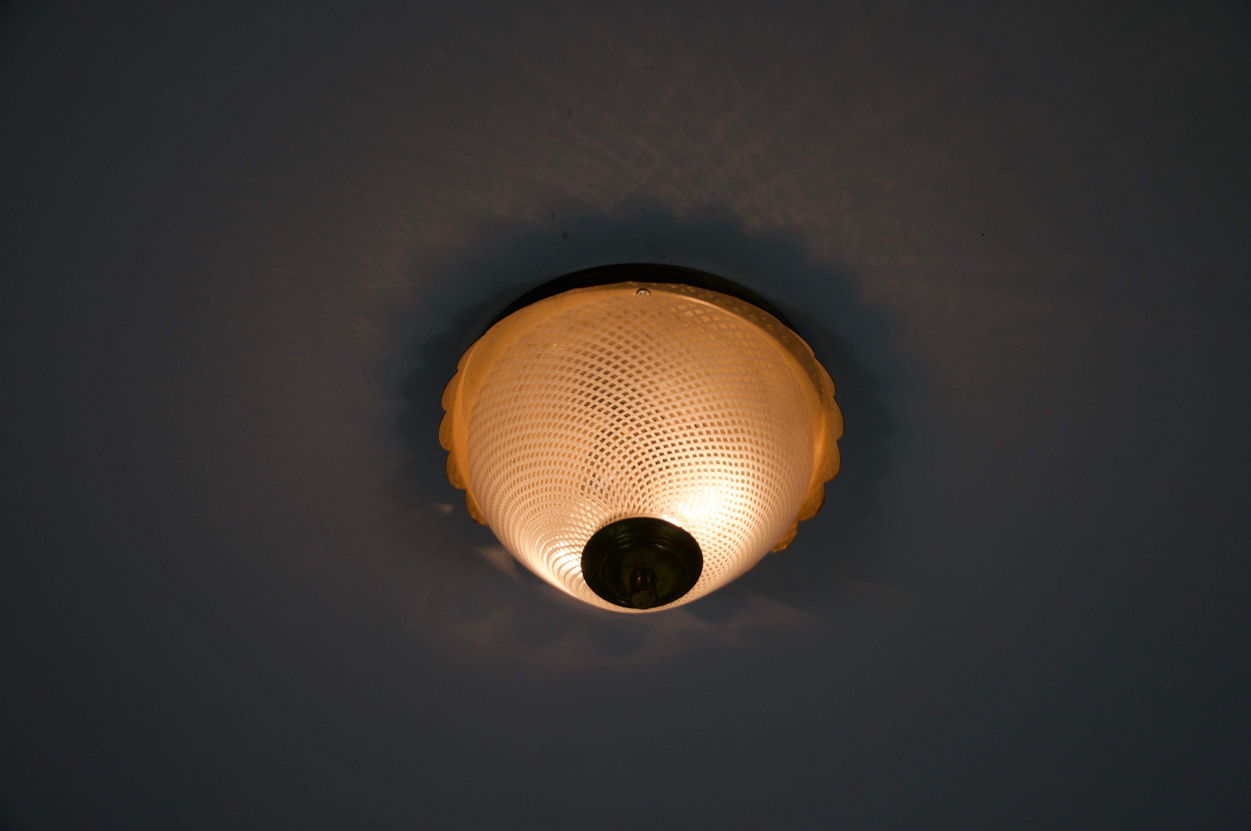 Esta elegante lámpara de techo redonda empotrada es un buen ejemplo del diseño italiano de mediados de siglo de la década de 1960. La lámpara presenta un marco de latón bellamente elaborado con un borde suavemente festoneado, que añade un toque de