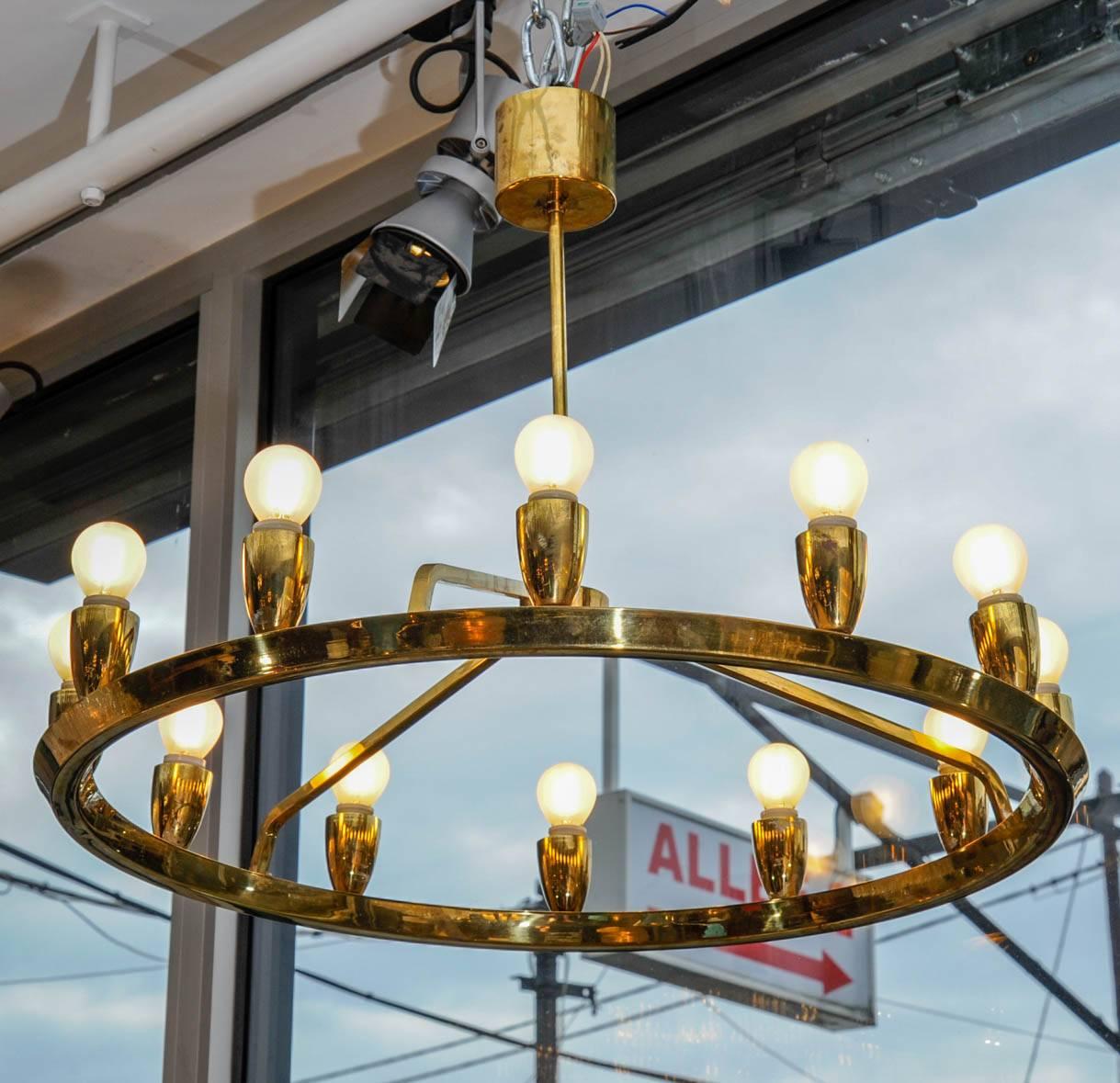 Swedish chandelier made of brass, a single stem from where leave three small arms holding a circle with twelve lamps, giving an overall crown shape.