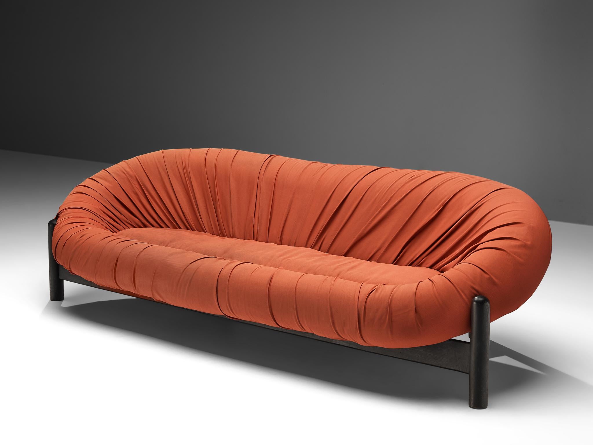 Sofa, lacquered wood, fabric, Brazil, 1970s 

This bulky Brazilian sofa consist of a round shell that forms an oval ring around the seat. The red fabric is tufted around the shell in dynamic folds. The shape invites to take a seat and relax. The