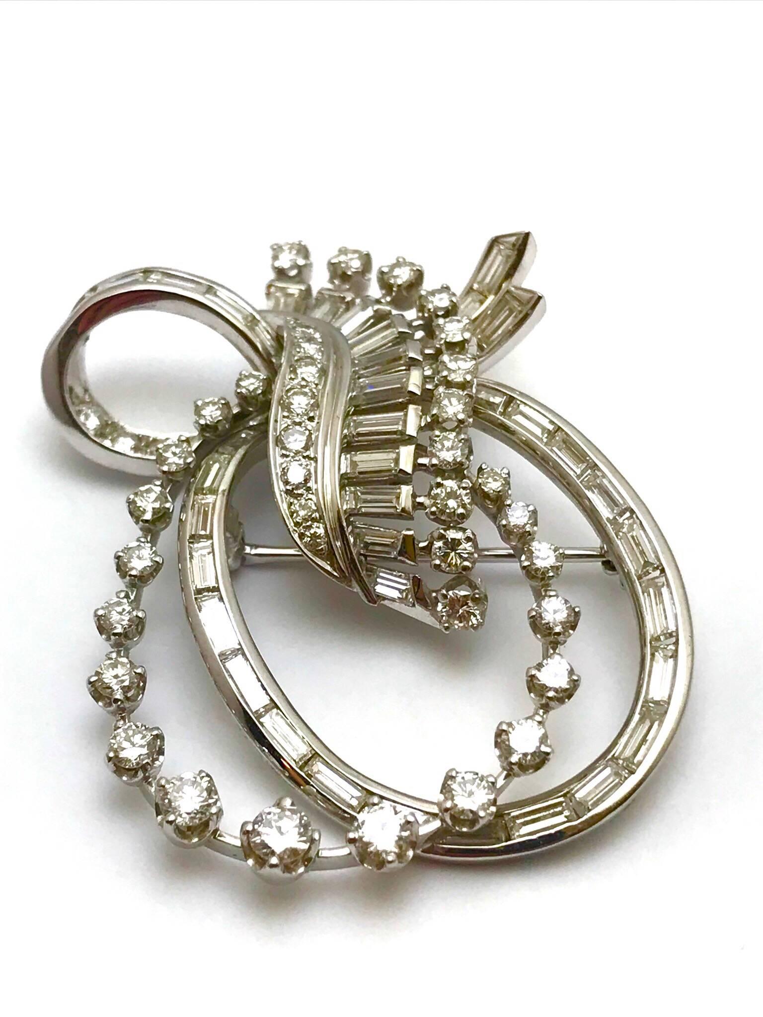 A round brilliant and baguette diamond platinum double bow pendant and brooch.  The baguette cut diamonds are channel set, with prong set round brilliant diamonds.  There is a total of 87 diamonds with a total weight of 5.26 carats.  The diamonds