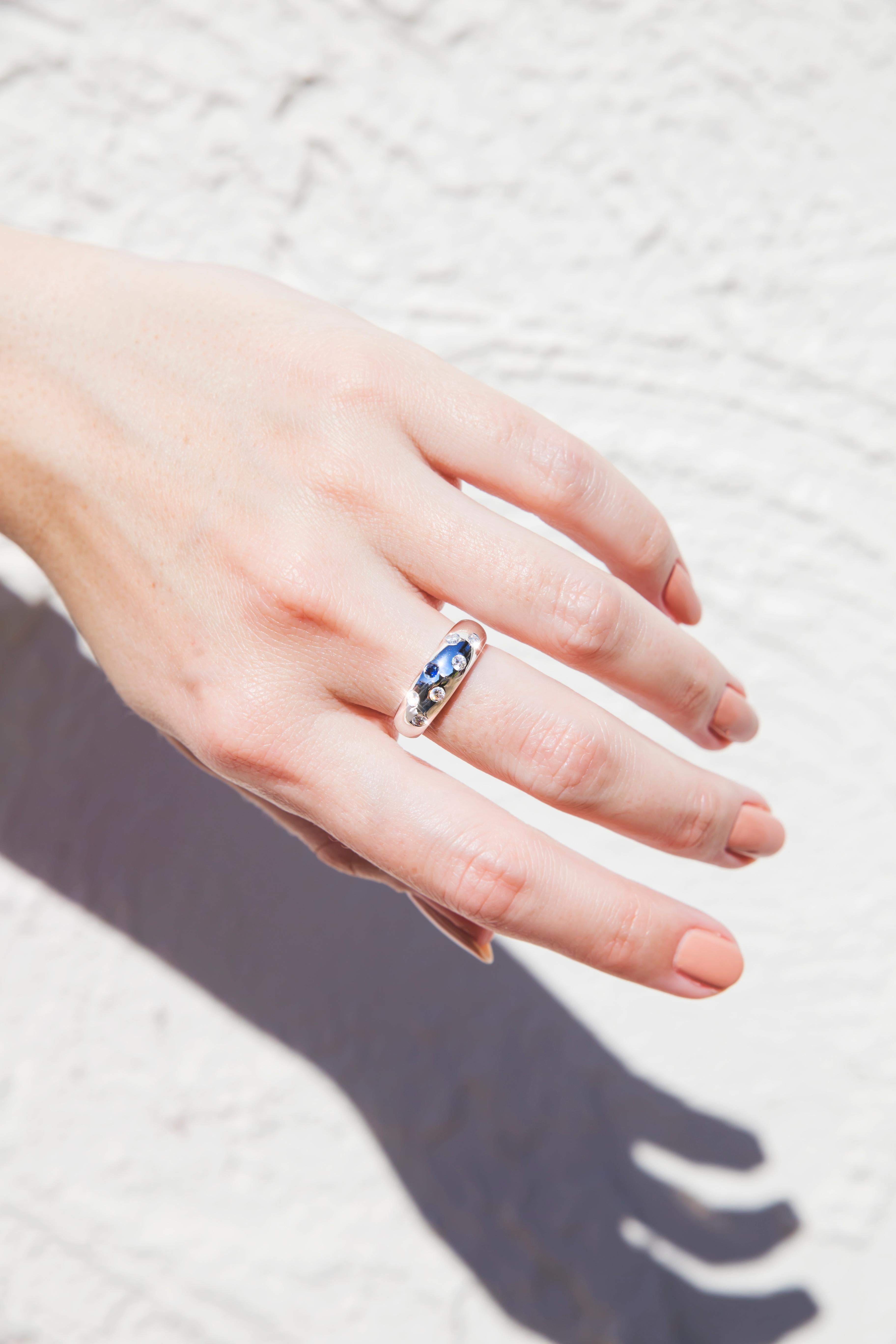 Carefully crafted in 18 carat white gold is this gorgeous diamond and sapphire dome ring features six hammer set handsome round brilliant cut diamonds and one single dark blue Sapphire.  We have named this darling piece The Belinda Ring. The Belinda