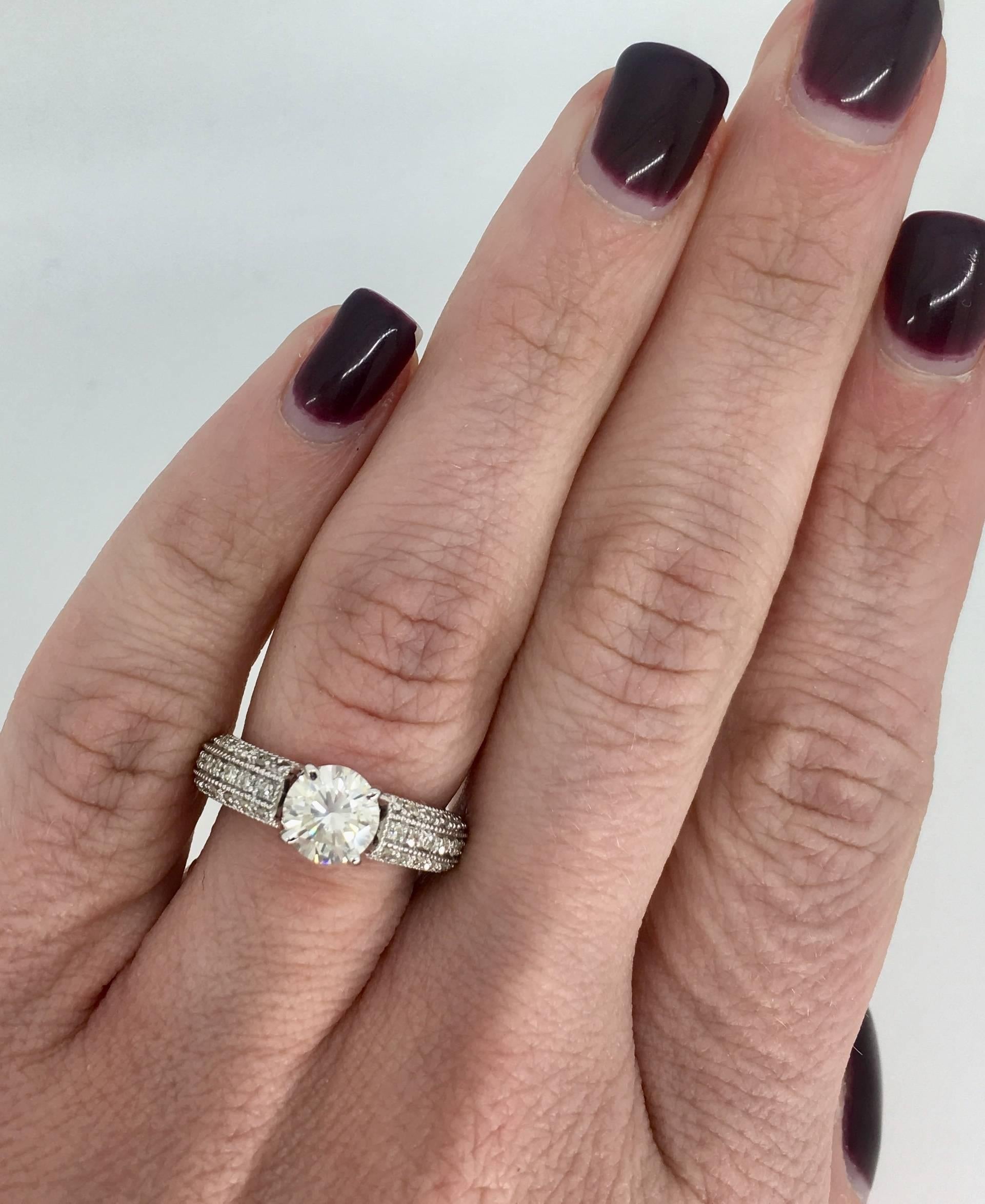 This beautiful ring features a 1.04CT Round Brilliant Cut Diamond that displays L color and SI2 clarity; the clarity grade of the diamond is based on the cloud inclusions present. There is an additional .42CTW of Round Brilliant Cut Diamonds set