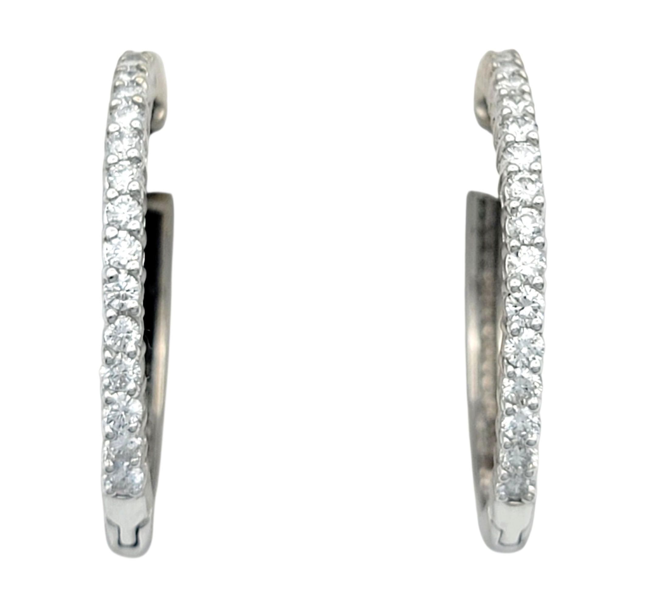 These 18 karat white gold hoop earrings are elegantly set with round brilliant cut diamonds, offering a seamless sparkle around their entire circumference. The slim yet substantial design makes them versatile for both casual wear and formal