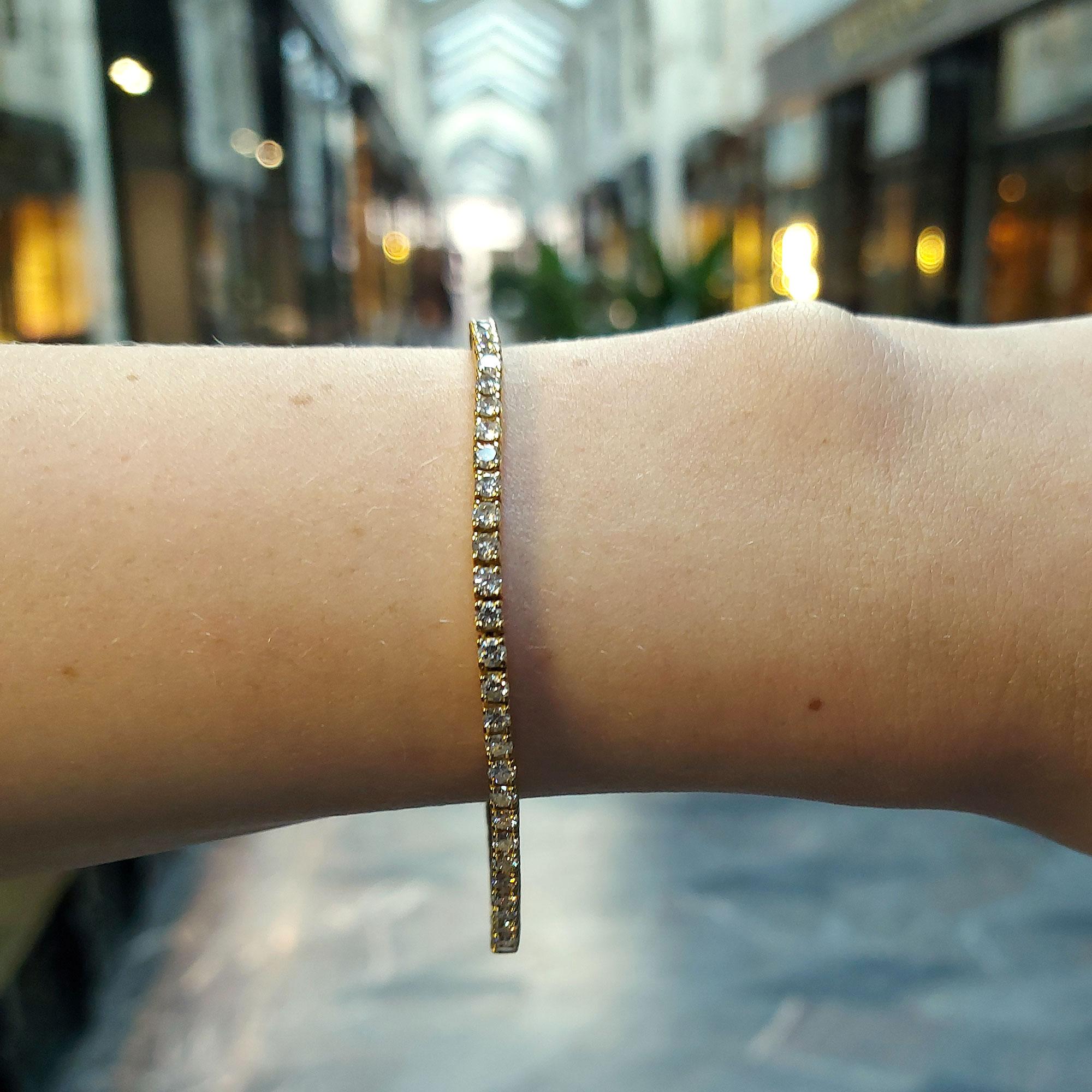 A classic diamond line bracelet in 18-karat yellow gold. 
This piece of jewellery features 60 round brilliant-cut diamonds all claw-set in individual articulated collets, leading to a click-shut clasp with a safety catch fitting. 

Diamonds