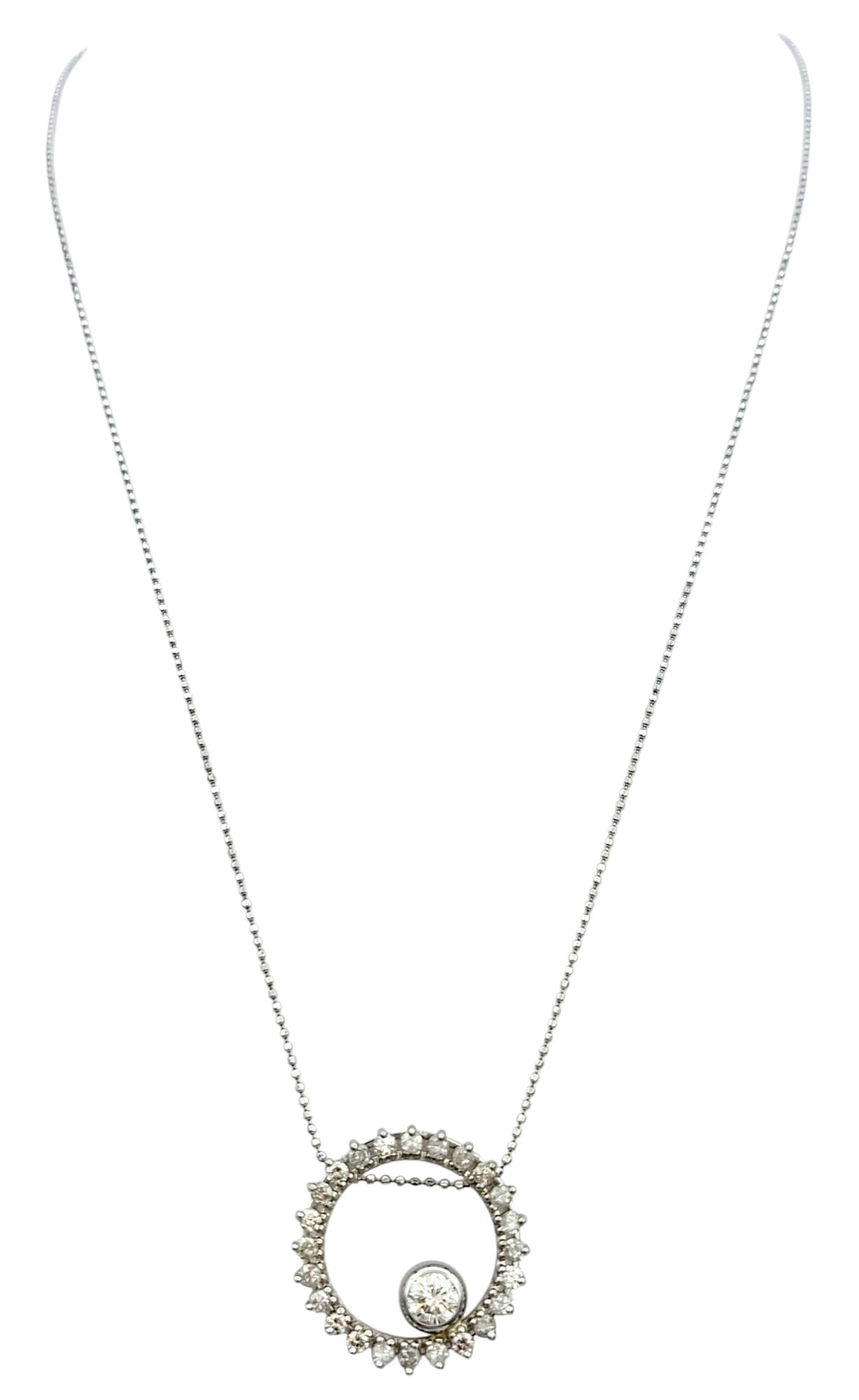 Delicato ma accattivante, questo ciondolo a cerchio aperto è realizzato in oro bianco 14 carati e brilla di un'eleganza senza tempo. Al centro, un diamante rotondo taglio brillante fluttua con grazia, distanziato per attirare lo sguardo e creare un