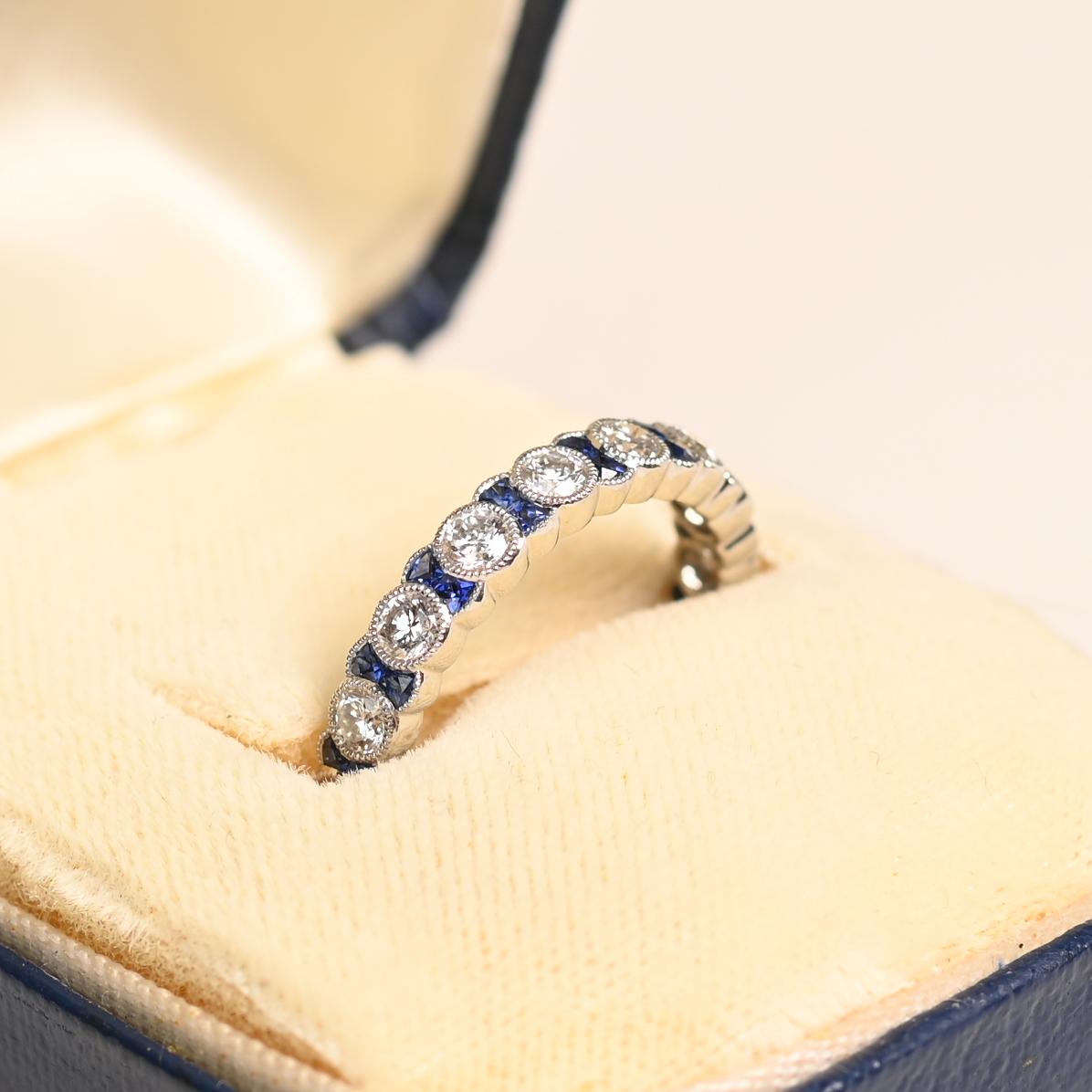 Este exquisito anillo de eternidad muestra una fascinante combinación de diamantes redondos talla brillante y zafiros meticulosamente calibrados. Elaborado a mano por expertos en platino, el diseño encarna la elegancia y la sofisticación