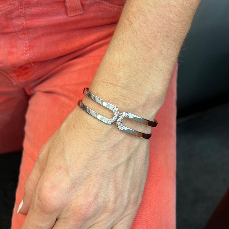 Modern diamond open cuff bracelet fashioned in 18 karat white gold. The bangle features 10 round brilliant cut diamonds weighing .50 CTW and graded G-H color and VS clarity. The open cuff measures 14mm in width, 2.25 inches in diameter, and will fit