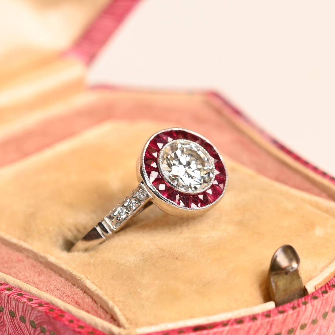 Este exquisito anillo de platino hecho a mano exhibe un impresionante halo de rubíes talla francesa meticulosamente dispuestos, rodeando con elegancia un deslumbrante diamante redondo talla brillante de 0,74 quilates. De color I y claridad VS2, el