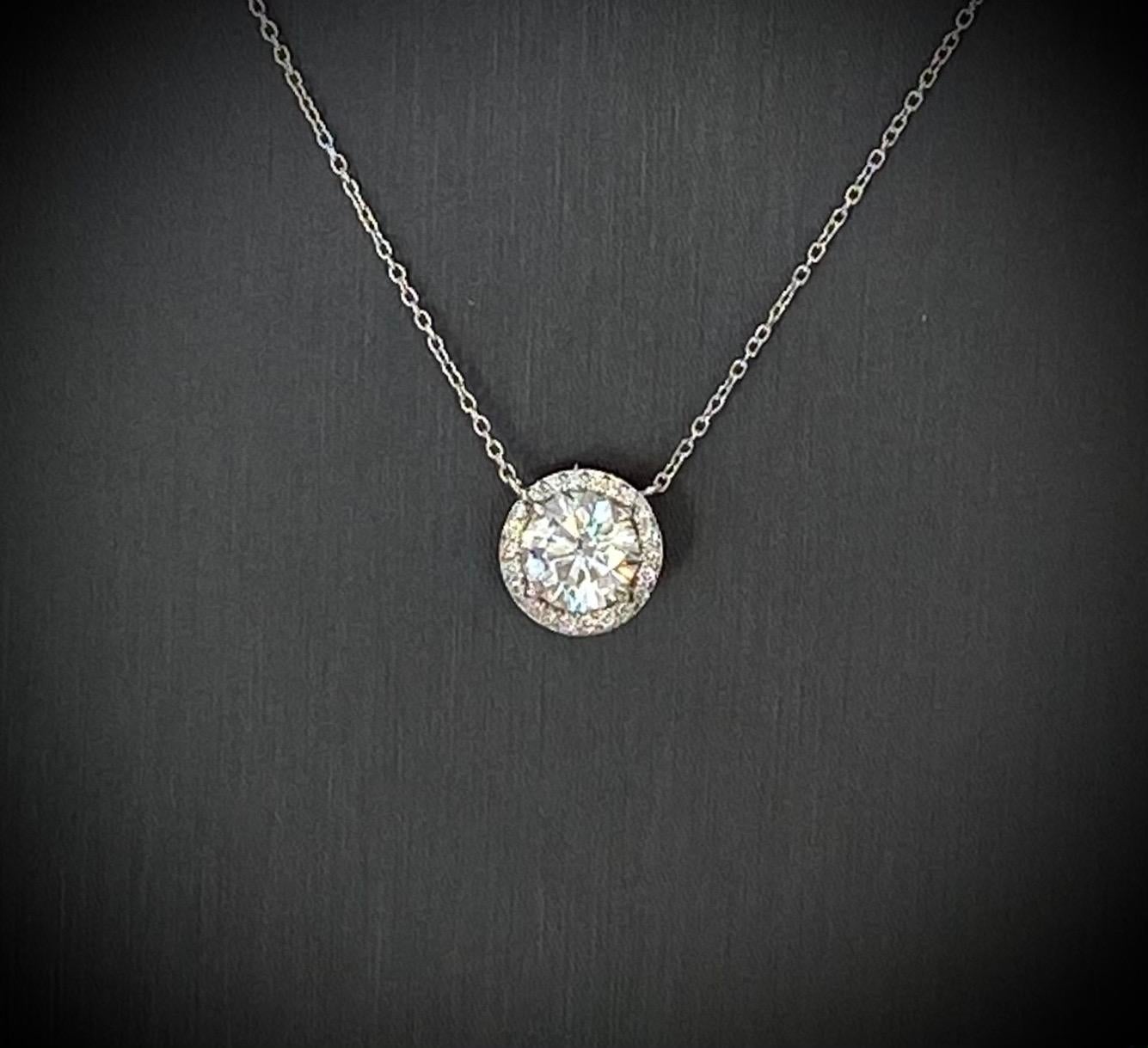 A stunning round brilliant cut diamond pendant with diamond surround set in platinum. The center diamond weighs 2.02 carats, is assessed as D color and SI1 clarity via GIA certificate. The stone is set in an elegant diamond surround finished with a