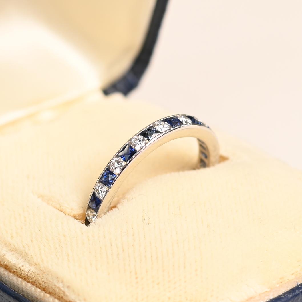 Esta exquisita banda de media eternidad está expertamente elaborada en lujoso platino, ofreciendo tanto elegancia atemporal como resistencia duradera. El anillo, una elegante fusión de diseño clásico y contemporáneo, presenta zafiros naturales talla