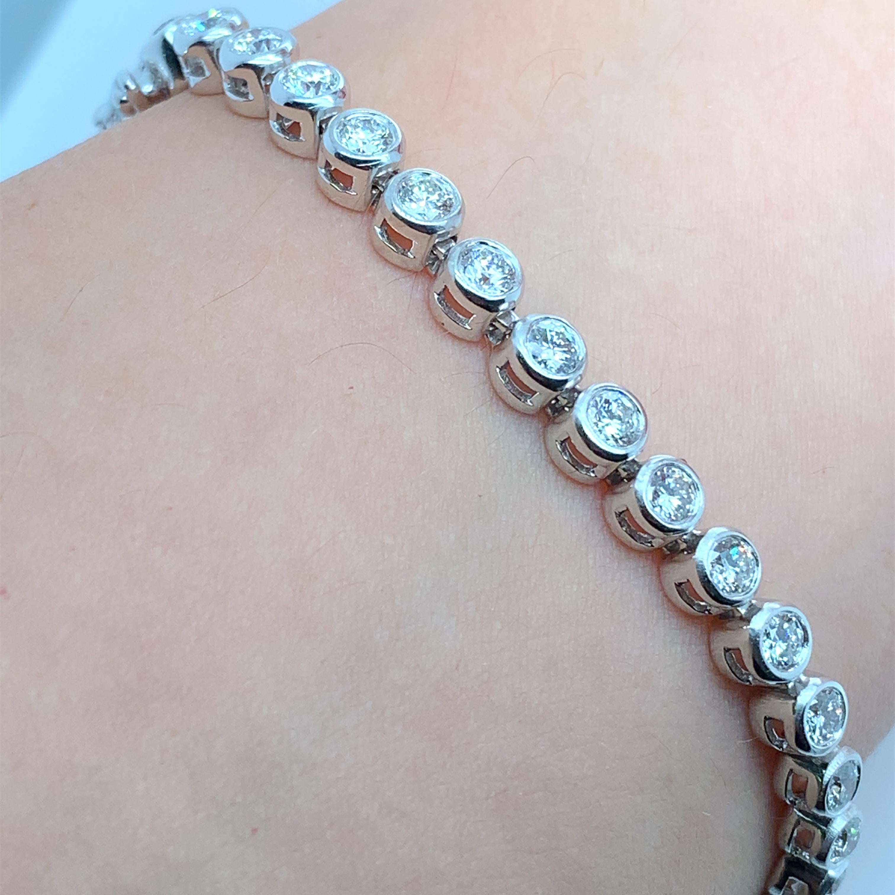 This stunning 5.20 carat round brilliant diamond tennis bracelet features a bezel rubover setting style and is crafted from 18k white gold. The bracelet is adorned with a beautiful pearl secondary stone and a lustrous pearl main stone. The brand of
