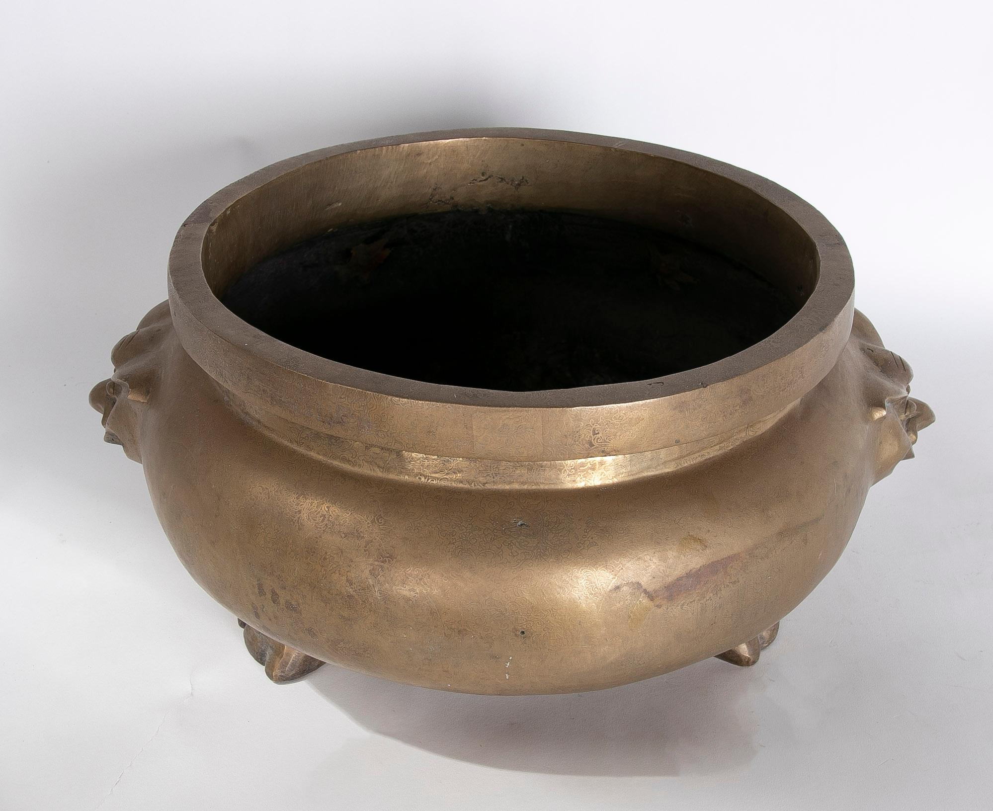 Round bronze vessel with two-sided decoration and foot-shaped feet.