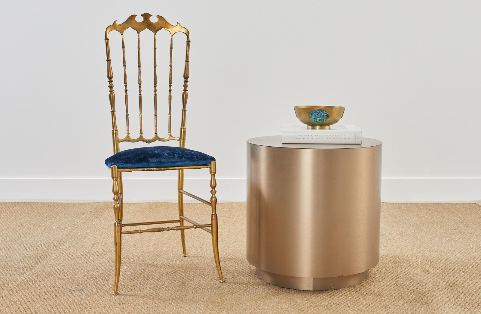 Modern style round pedestal display table or stand featuring a bronzed metallic metal veneer crafted from an MDF wood frame on a smaller base stand conjoined by roller bearings. The wood is wrapped with a steel veneer having a smooth brushed finish