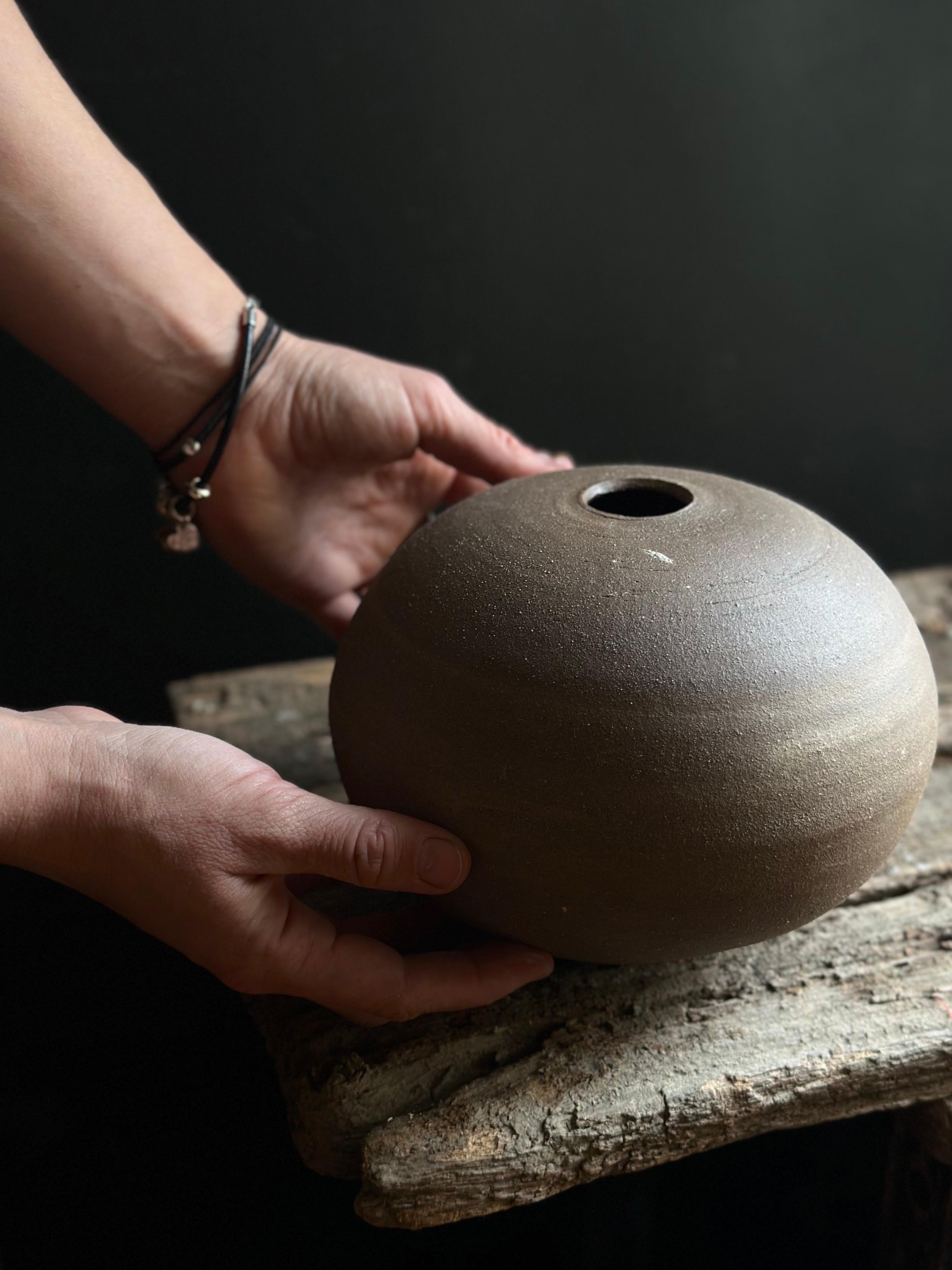 A minimalist, hand-thrown ceramic vase with a warm, unglazed surface that highlights the natural beauty of the clay. Its understated, organic form is perfect for interiors that embrace earthy tones and textures, such as Scandinavian, Japandi, or