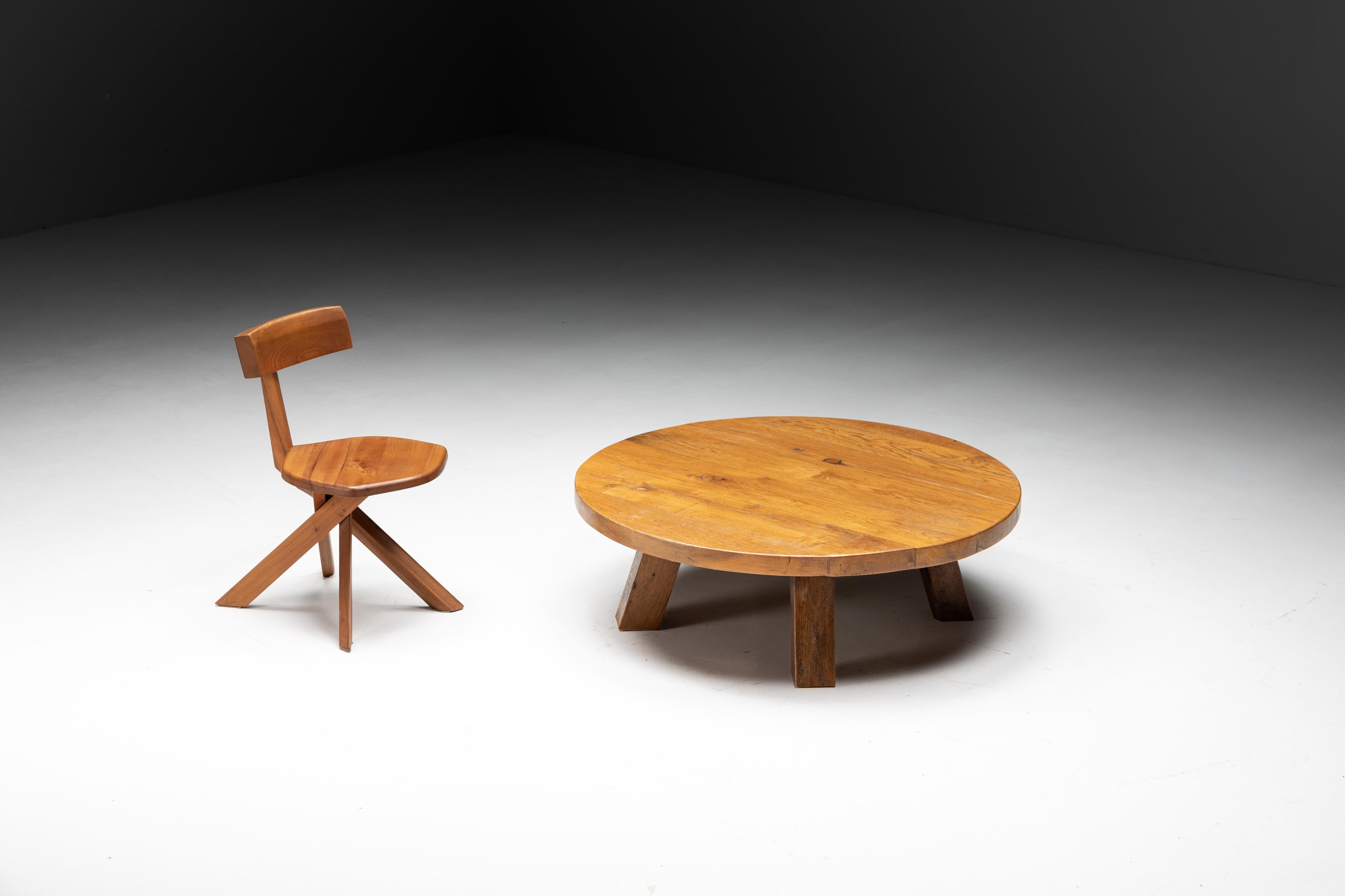 Table basse ronde en bois brutaliste avec une base à quatre pieds, fabriquée en bois massif avec une patine charismatique. Sa surface offre un large espace pour mettre en valeur vos livres préférés, vos souvenirs précieux ou tout simplement pour