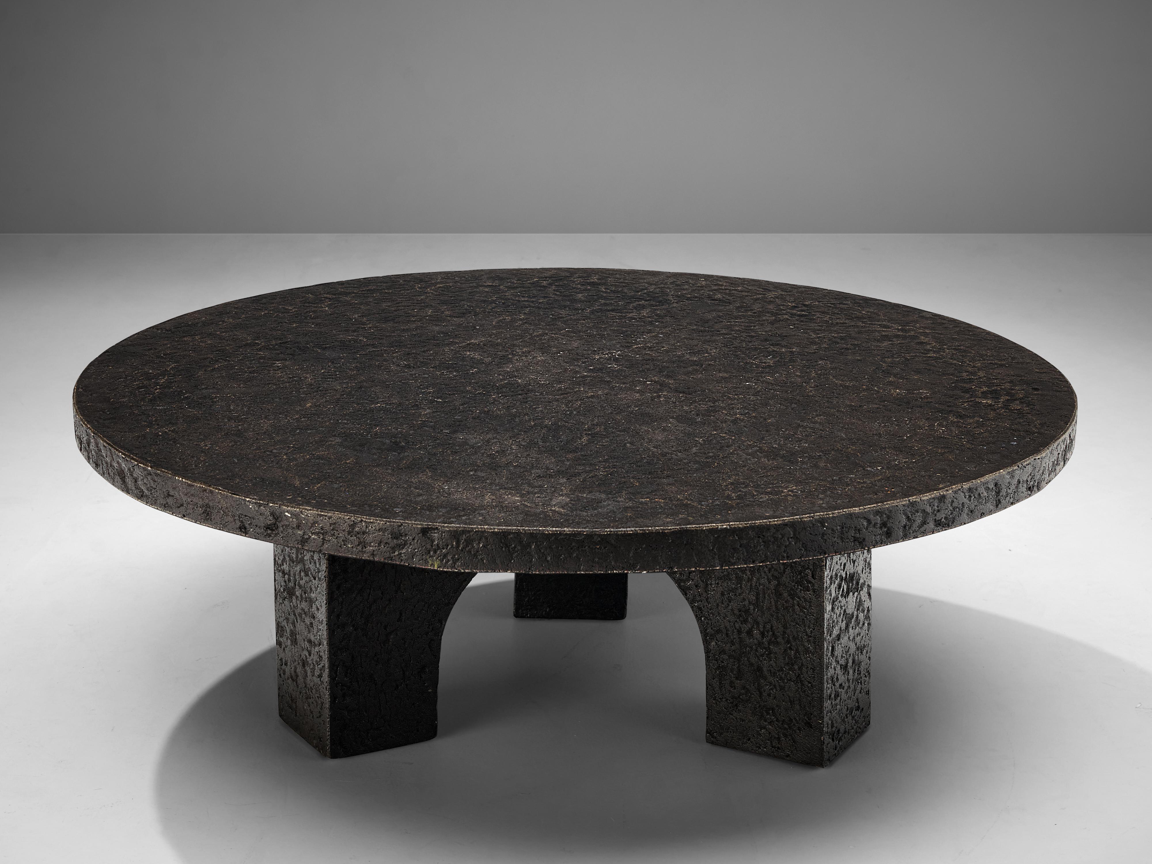Coffee table, resin, Northern-Europe, 1970s.

This deep black to brown coffee or cocktail table was made in the 1970s. The thick round top is supported by three arched legs that contribute to the sturdy, architectural appearance. This low table is