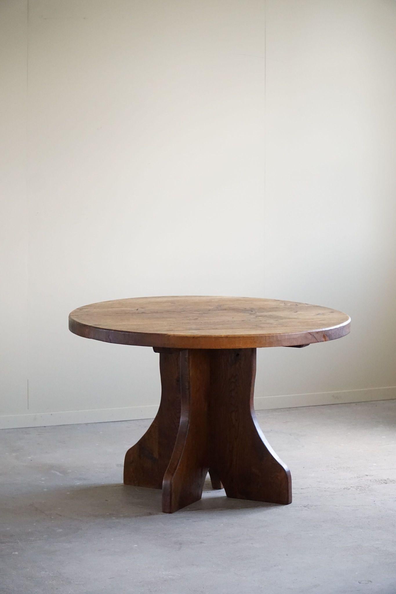 Impresionante mesa de comedor redonda de roble macizo de estilo brutalista, fabricada en Francia en la década de 1960 por un ebanista francés. Esta pieza moderna de mediados de siglo presenta un diseño robusto y minimalista, que enfatiza las