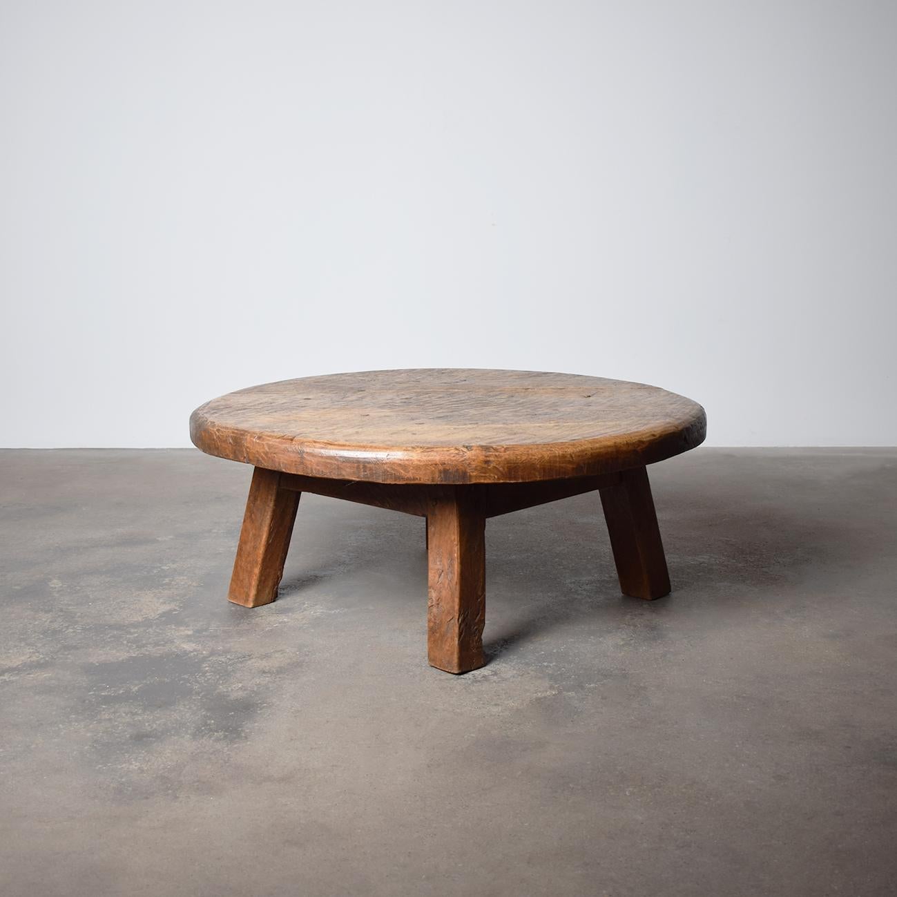 Questo tavolino da caffè rotondo in stile brutalista francese del Mid-Century è uno straordinario esempio di design audace che incontra una raffinata maestria artigianale. Realizzato in rovere massiccio, il tavolo presenta una caratteristica